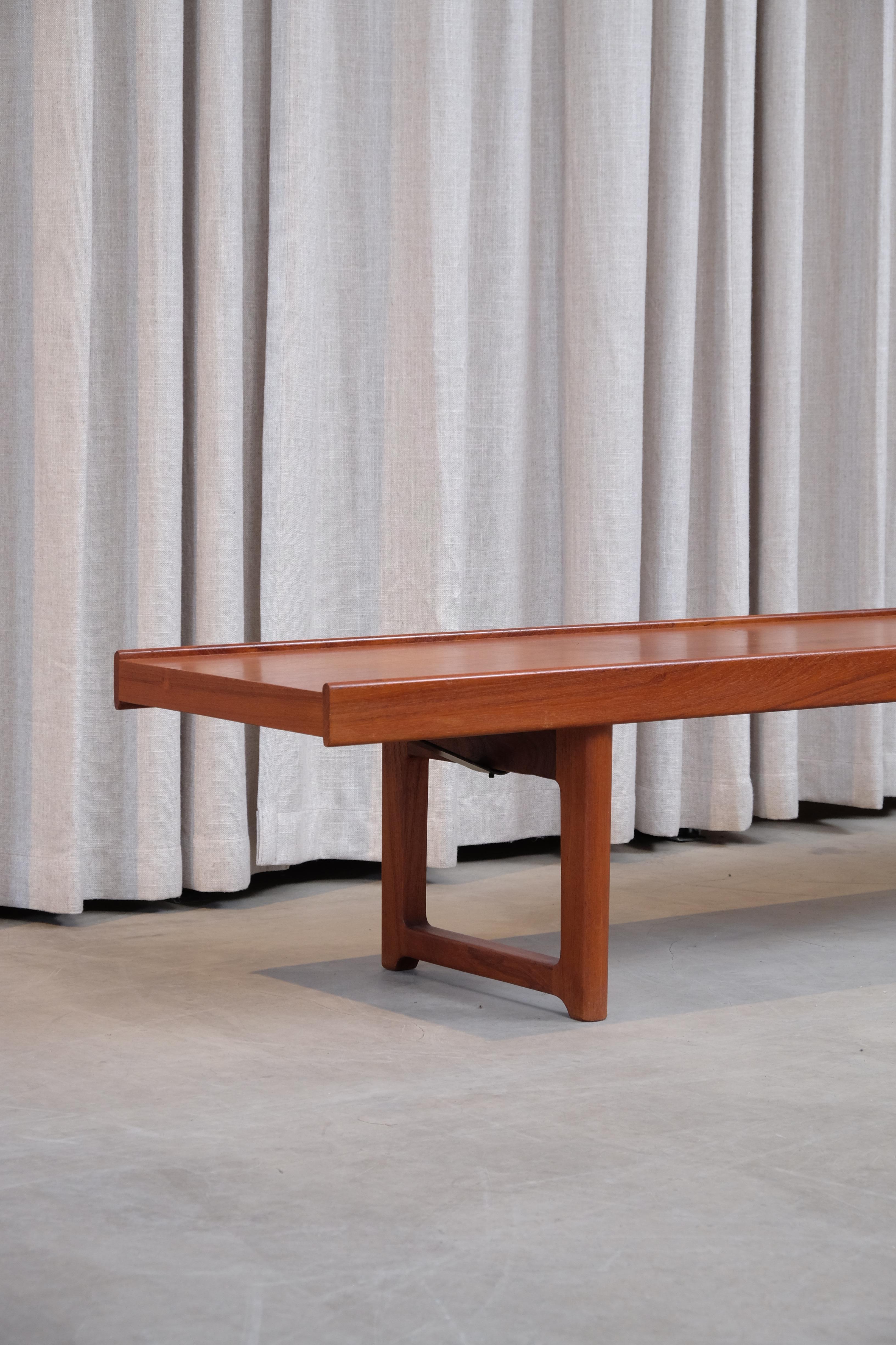 A Scandinavian Modern bench in a simple plank form in teak with two raised edges then resting on legs that join at the floor creating U-shaped pedestal bases. By Torbjörn Afdal for Mellemstrands Trevareindustri and distributed by Bruksbo Møbler,