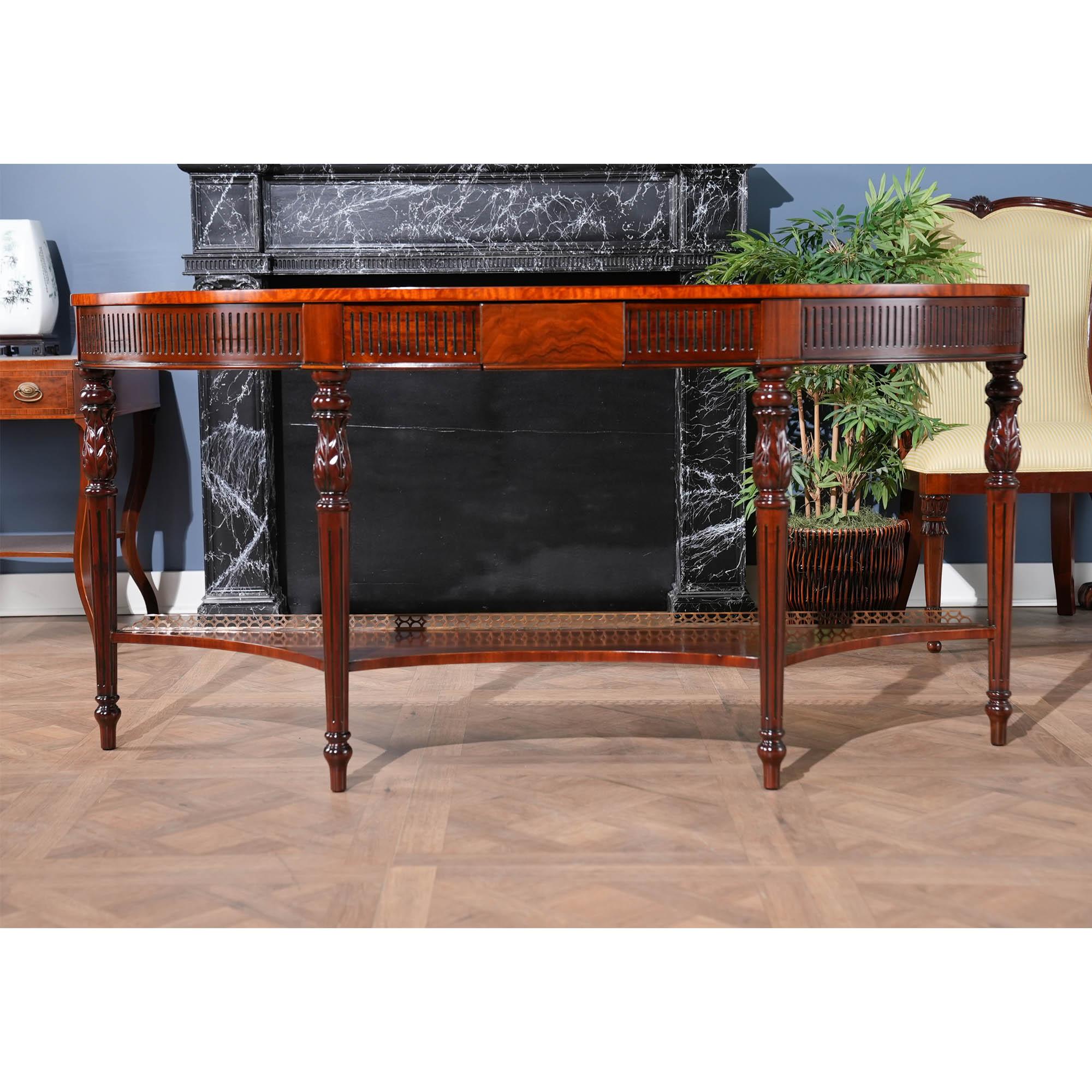 Una consola larga de caoba excepcional y de gran calidad, de Niagara Furniture. La Consola Larga de Caoba con Galería de Latón también hace un elaborado uso de incrustaciones, tallas y molduras. La tapa de caoba tiene bandas de madera satinada, las