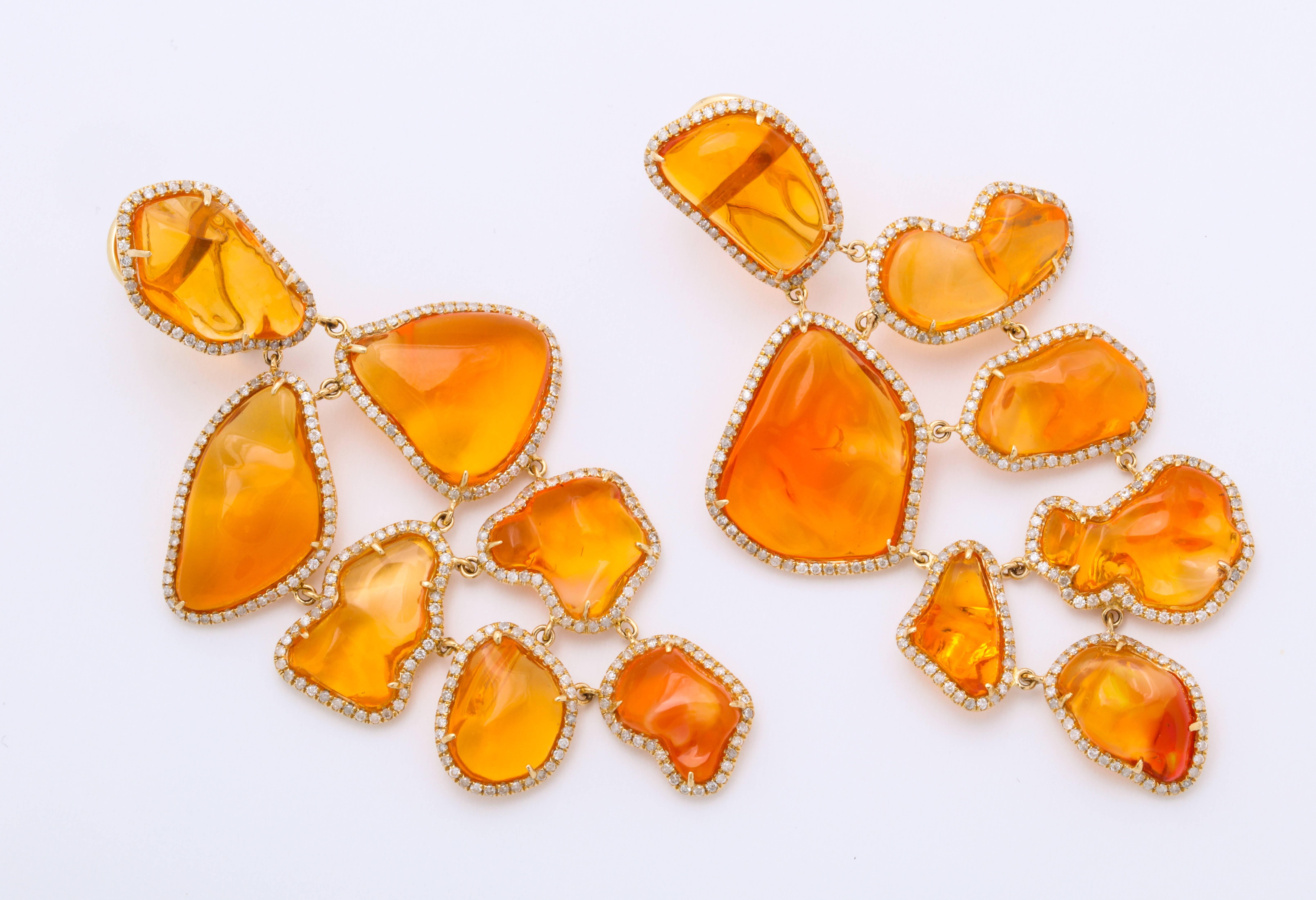 18kt yellow gold, Mexican fire opal (14=52.08cts) and diamond (0.69cts) long hanging earclips.  Each of the fourteen uniquely cut fire opals is precisely set, and perfectly surrounded by diamonds.  The stones are each carefully linked together,