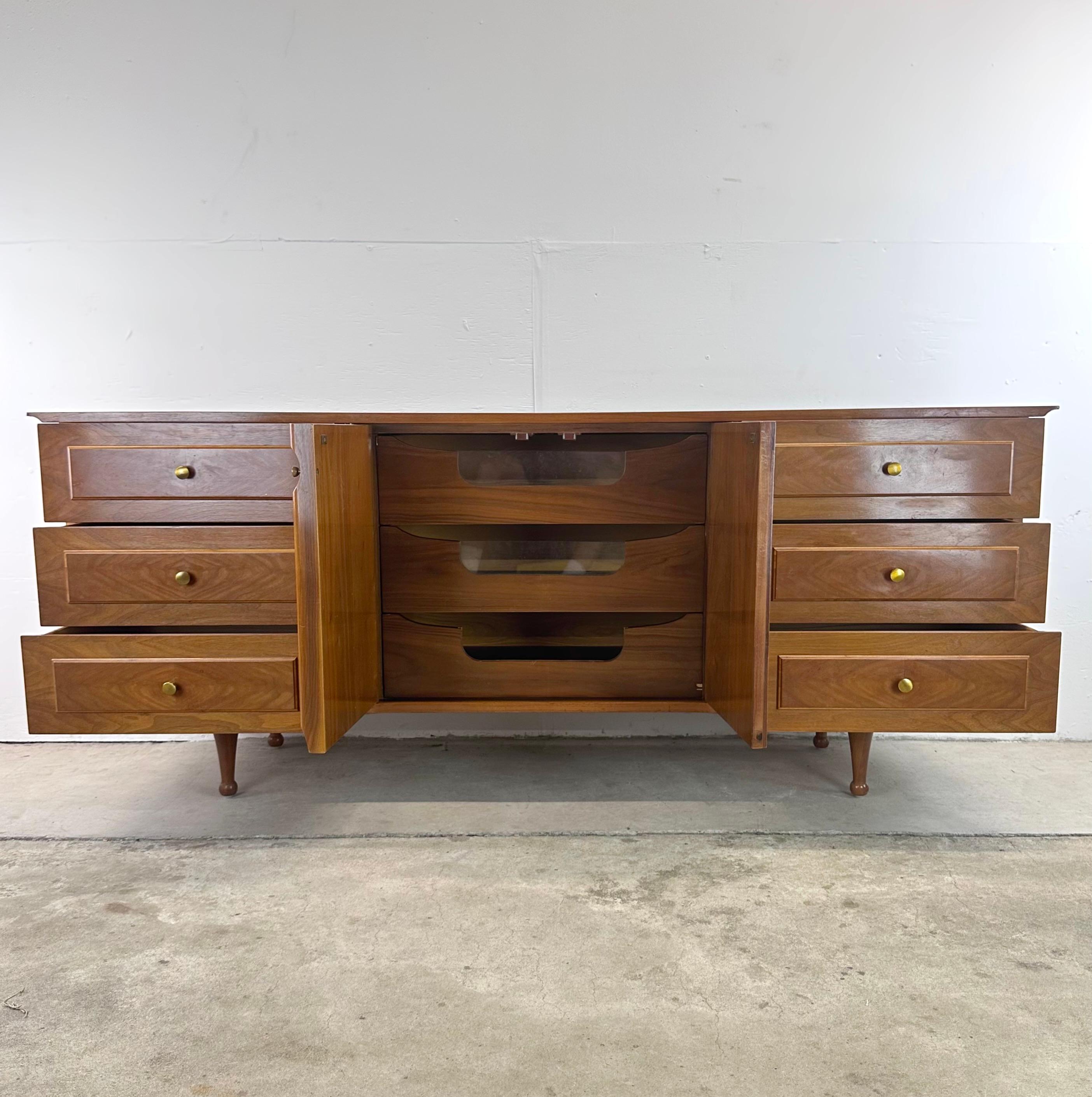 This Mid-Century Nine Drawer Lowboy Dresser is a remarkable piece that seamlessly merges timeless elegance with modern functionality. Crafted with meticulous attention to detail, this dresser is a tribute to the golden era of mid-century design and