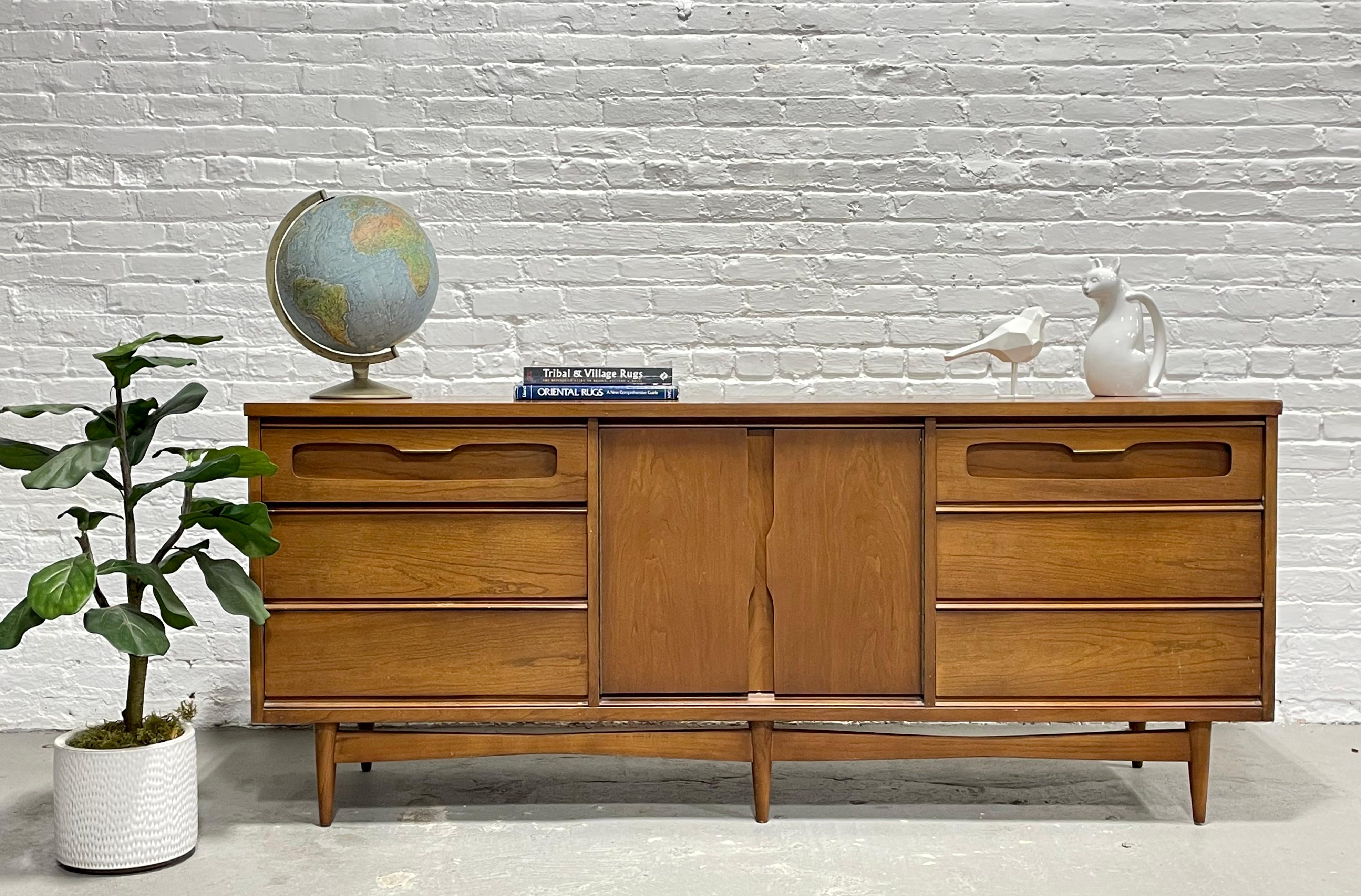 Mid-Century Modern Long Walnut Dresser by Bassett Furniture Co., circa 1960s. This long dresser packs a punch with a total of 8 deep and spacious drawers for all your clothing storage needs. Good original condition with some touch-ups and signs of