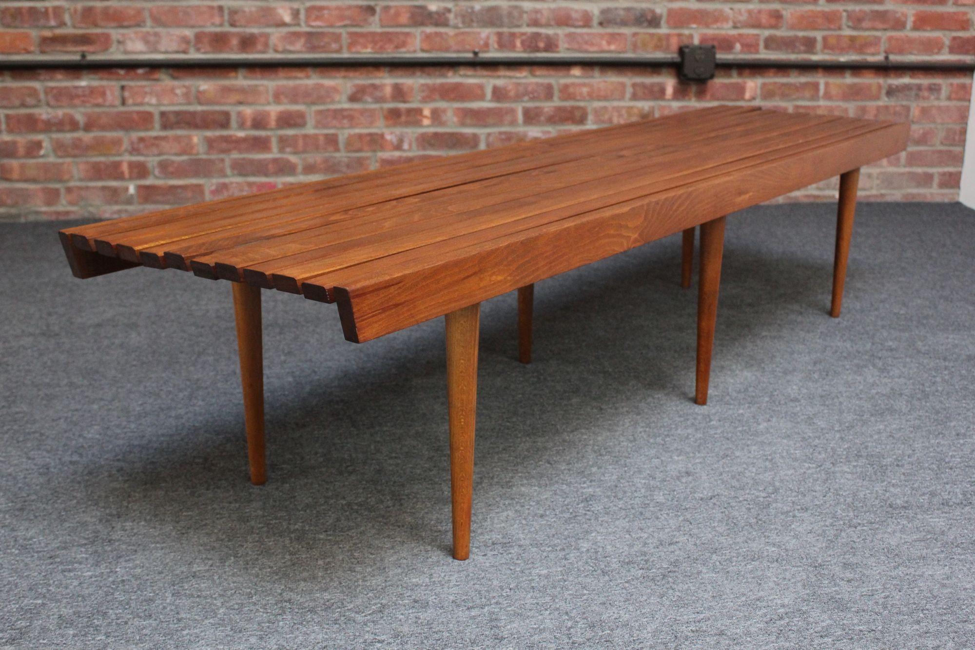 Classic Mid-Century American Modern slatted walnut bench or coffee table supported by six, slim, tapered legs (ca. 1950s, USA).
Newly refinished condition but light wear and slight warping to some of the slats remain (warping is subtle and typical