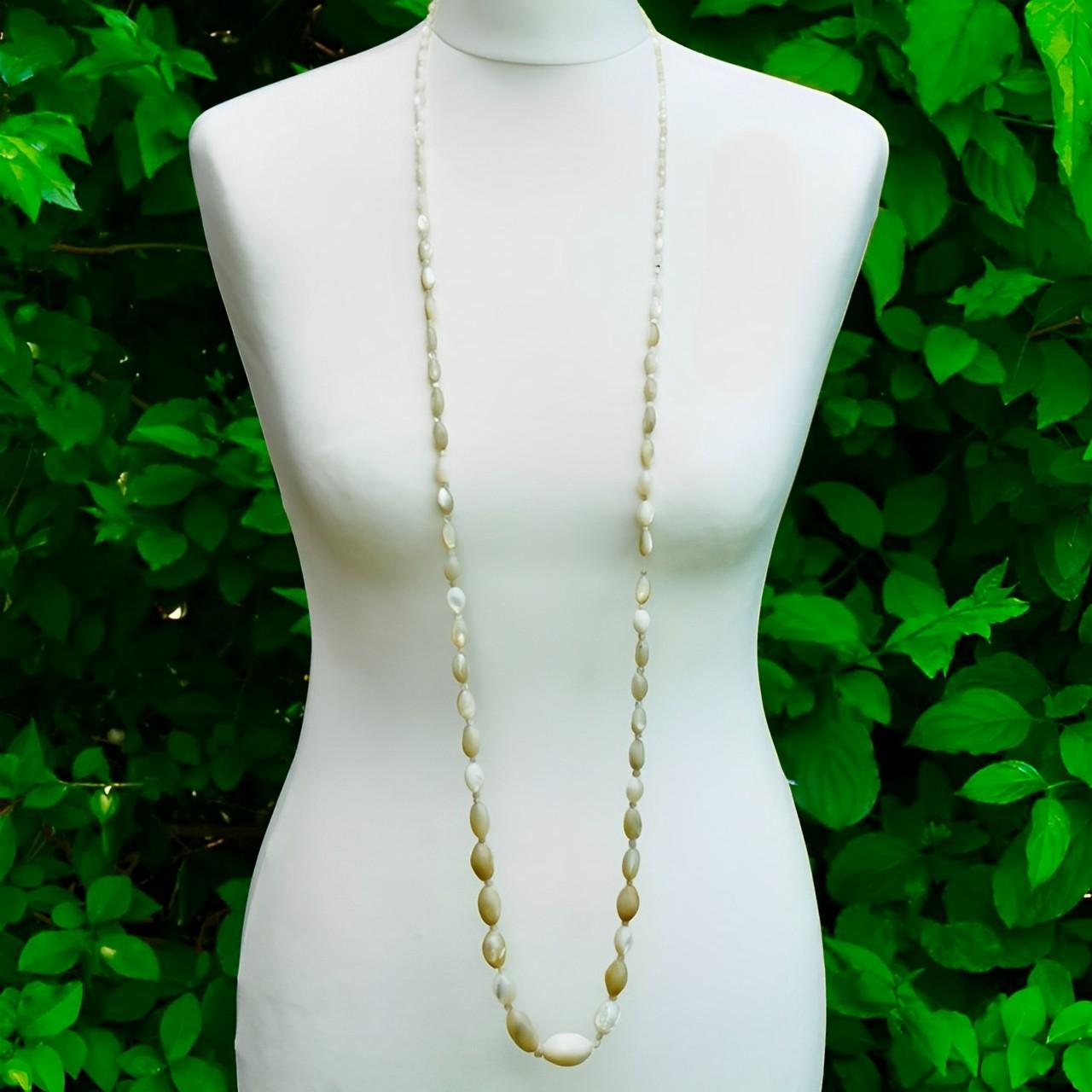 

Lovely long mother of pearl necklace with oval shaped beads, small mother of pearl spacers., and a rhinestone set clasp. Measuring necklace length 130 cm / 51 inches. 

The necklace has graduated sized beads. It has been re-designed and restrung