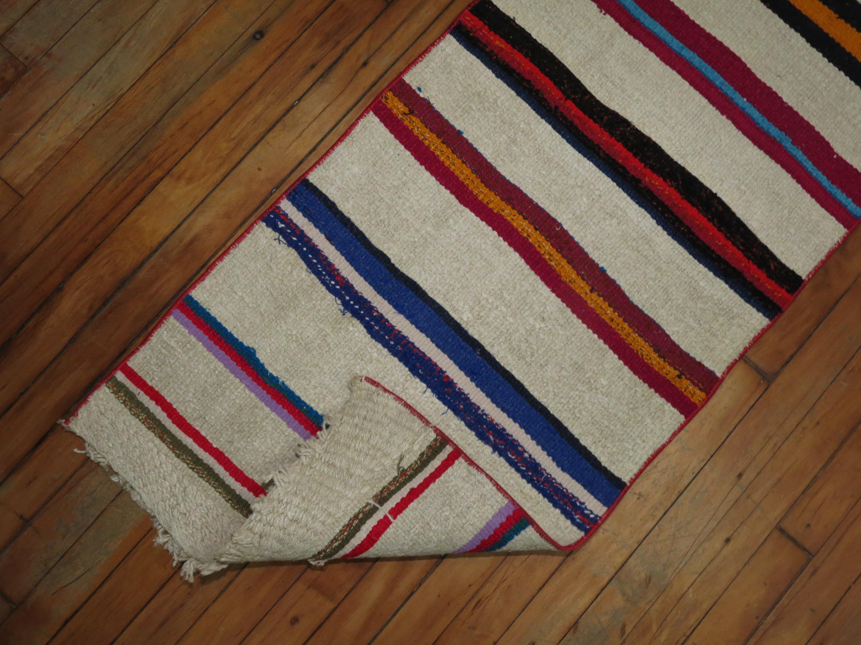 Colorful casual long Kilim runner from the mid-20th century. Bright pinks, black orange, lime green, fuchsia highlight the color accents on an ivory ground.

Measures: 1'10” x 21'1”.