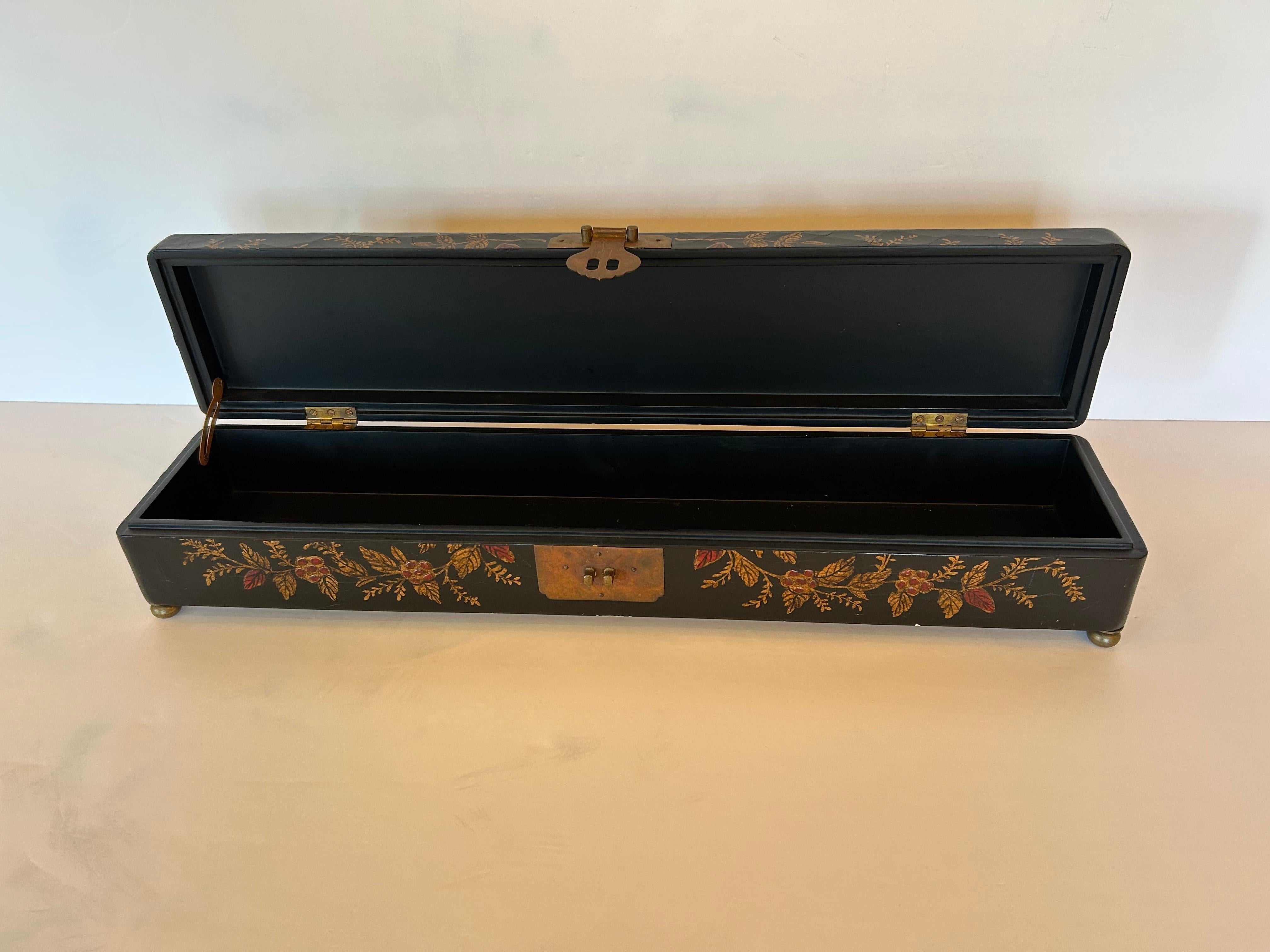  Graziosa scatola Chinoiserie insolitamente lunga e stretta, con sfondo nero e fiori rossi e dorati, cerniera in ottone e piedini a conchiglia.
