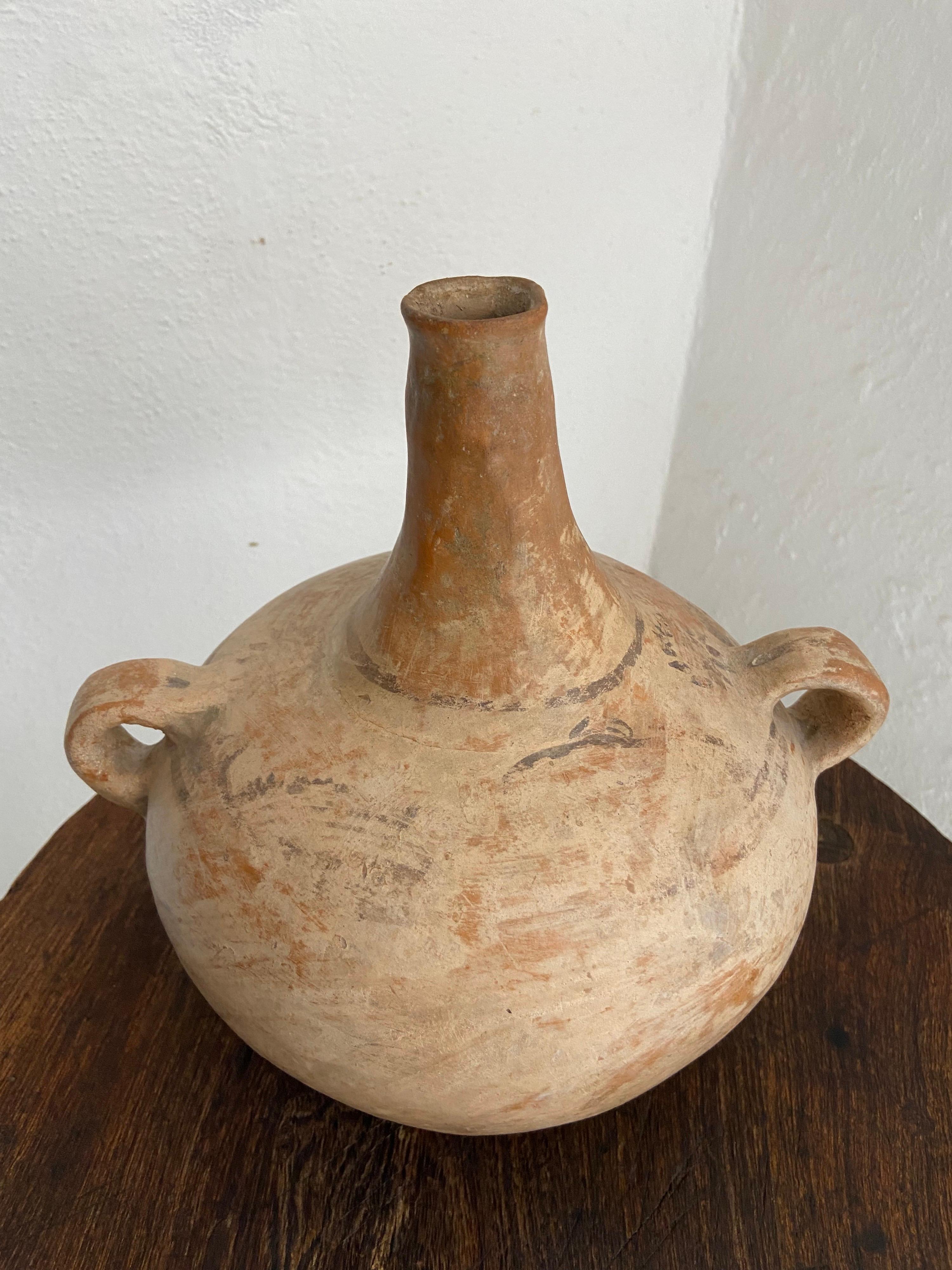 Long necked water jug from Mexico's Huasteca region. This style of hand crafted pottery is generally from the remote town of Chililico. Nahuatl is predominantly the indigenous language spoken in the area. Hand painted flowers on the body of the pot