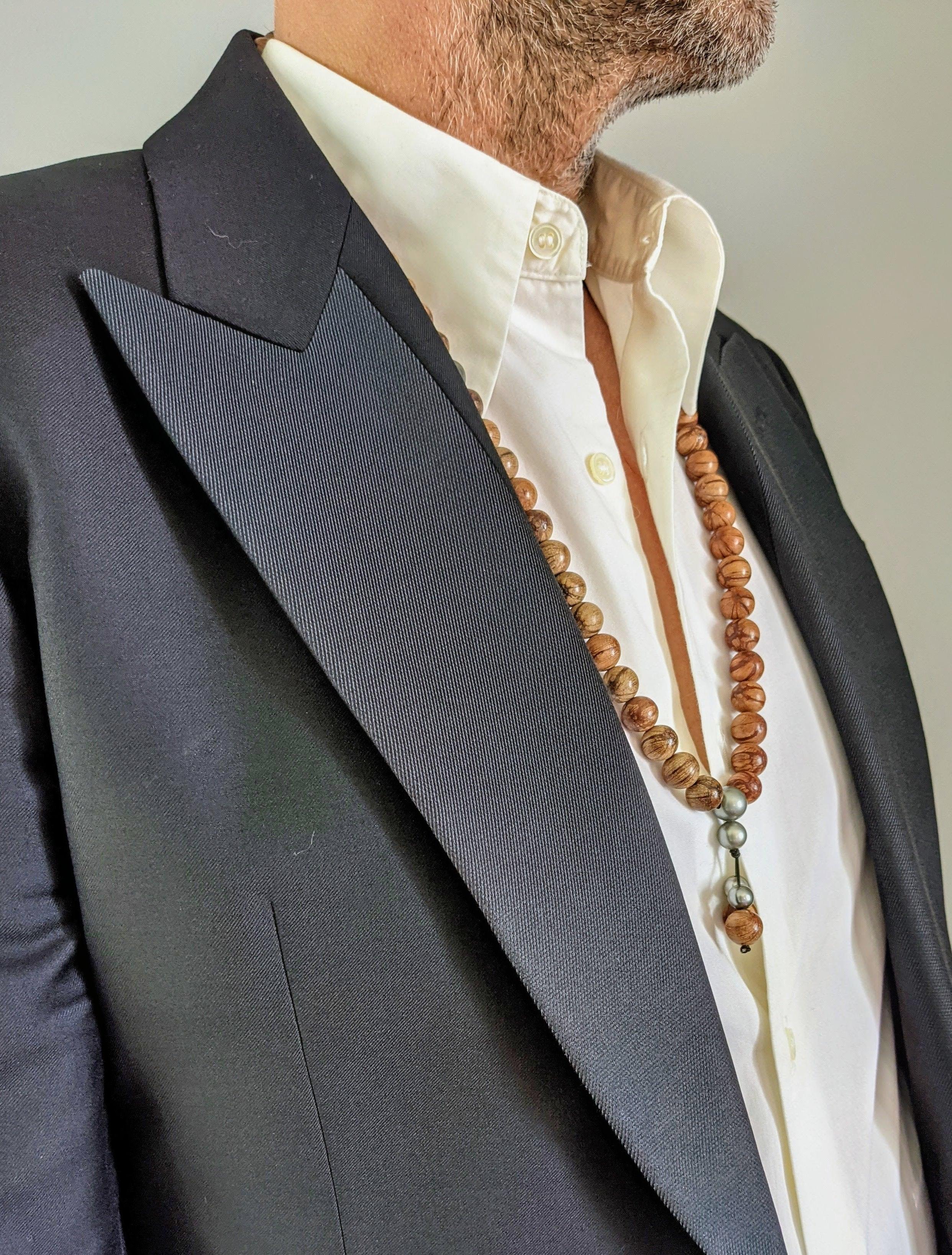 Ce collier est composé de perles en bois d'Abélia très légères d'un diamètre de 12 mm et de 6 belles perles de Tahiti.

Le collier offre un design audacieux et époustouflant inspiré des colliers de prière bouddhistes. Les perles et les perles sont