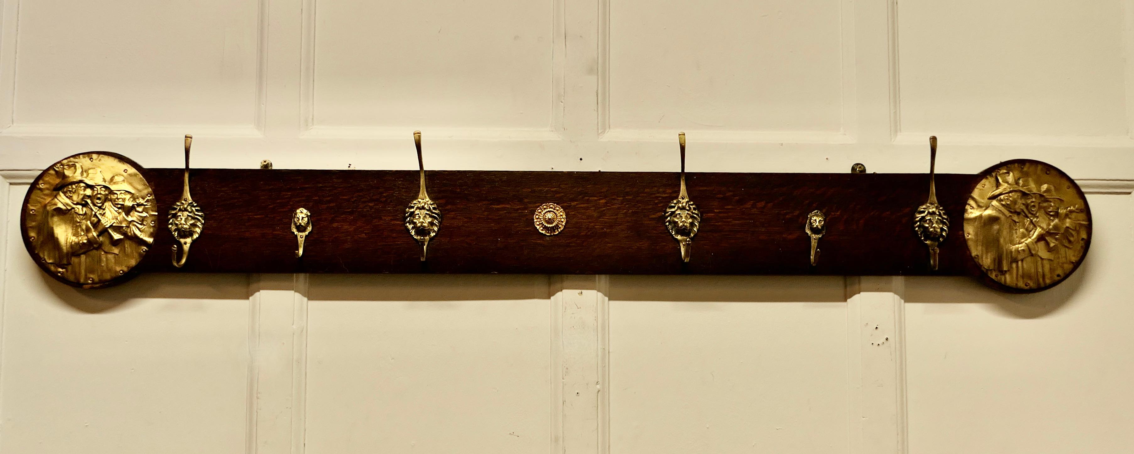 Long Oak Pub Coat Rack, with Lion’s Mask Hooks

A long piece of solid oak with both large and small brass lions mask coat pegs and round end plaques with some very jolly musicians

The Coat rail is 61” long and 9” high and 3” deep on the wall
SW235