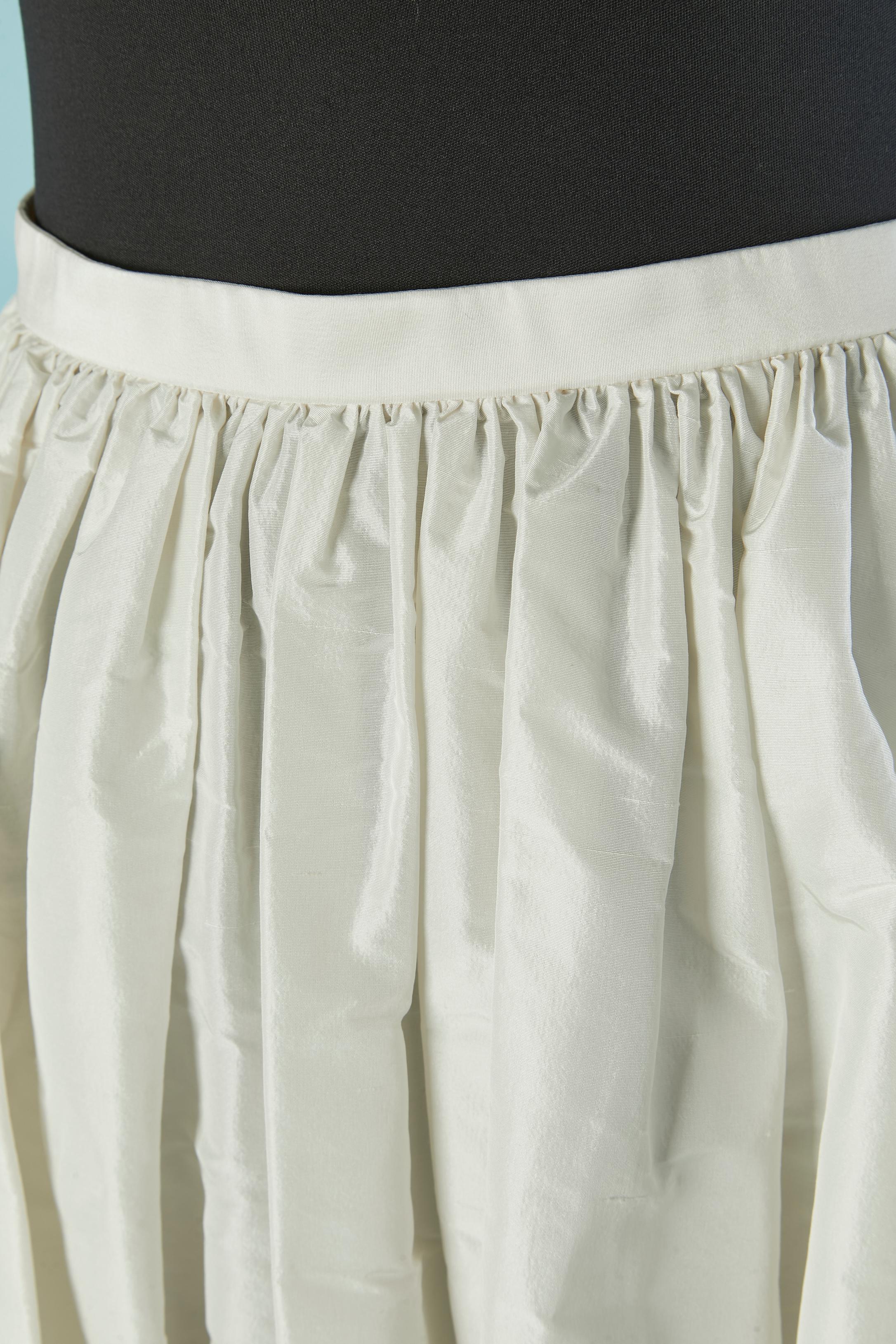 Longue jupe en soie grège blanc cassé, froncée à la taille. Fermeture à glissière invisible et crochet sur le côté gauche. 
Pochette sur les deux côtés. 
TAILLE 34 (Fr) XS 