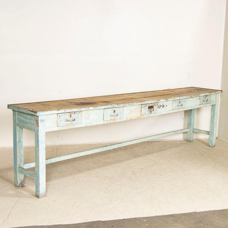 For those who search for a unique console table this long original blue painted worktable is a special find. The wonderful, age-distressed blue paint of the base (including paint spills and distress) is complimented by the pine plank top that