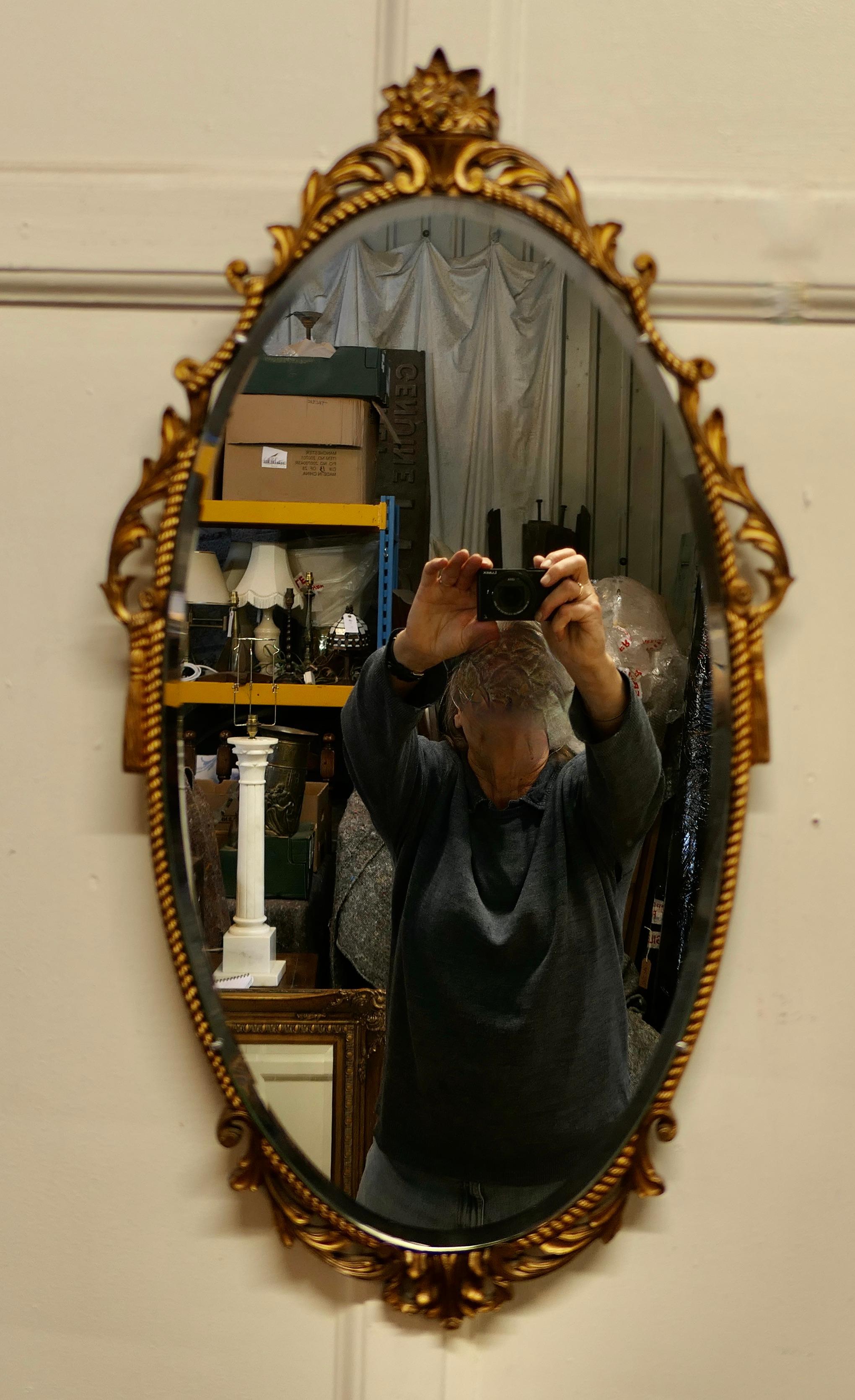 Long oval Art Deco Atsonea ornate gilt wall mirror

The Mirror is Oval it has a decorative Art Deco Rococo gilt Frame with surrounds a bevelled glass mirror.
The mirror glass is original and in good condition with little or no foxing.
The Mirror