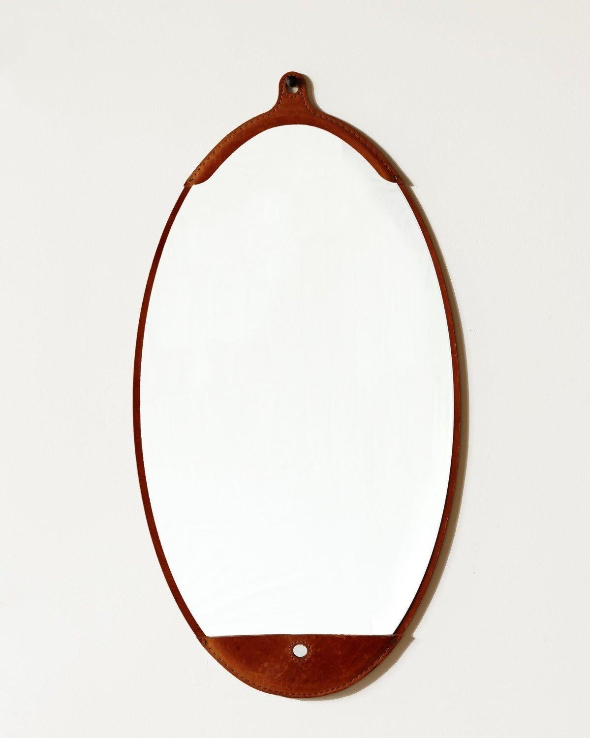 The Fairmount wide oval mirror is a hand-stitched leather mirror with a frame made from natural vegetable tanned leather which will vary in color and darken slightly with age. The mirror sits inside the frame like a pocket. It comes with an iron