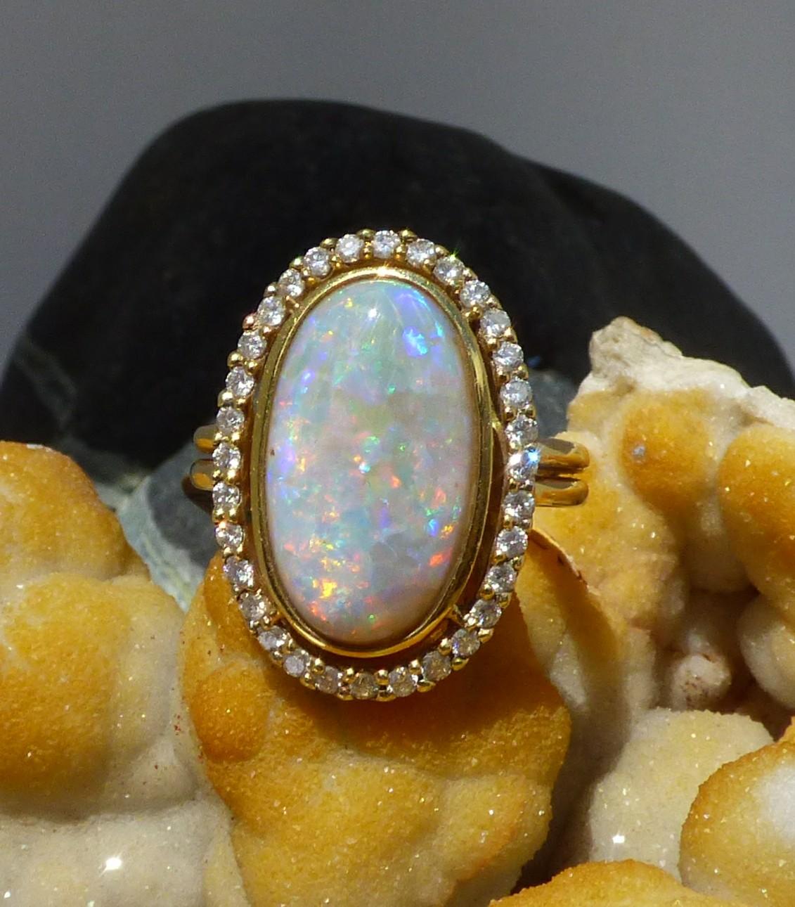 Long oval Opal showing very good colours (5.79ct.) is surrounded by Diamonds (.57ct.) in our handmade 18K yellow gold ring. The cluster is 23X16mm in size. If this ring is exported outside the EU, we will deduct the Irish Sales Tax (VAT) which is