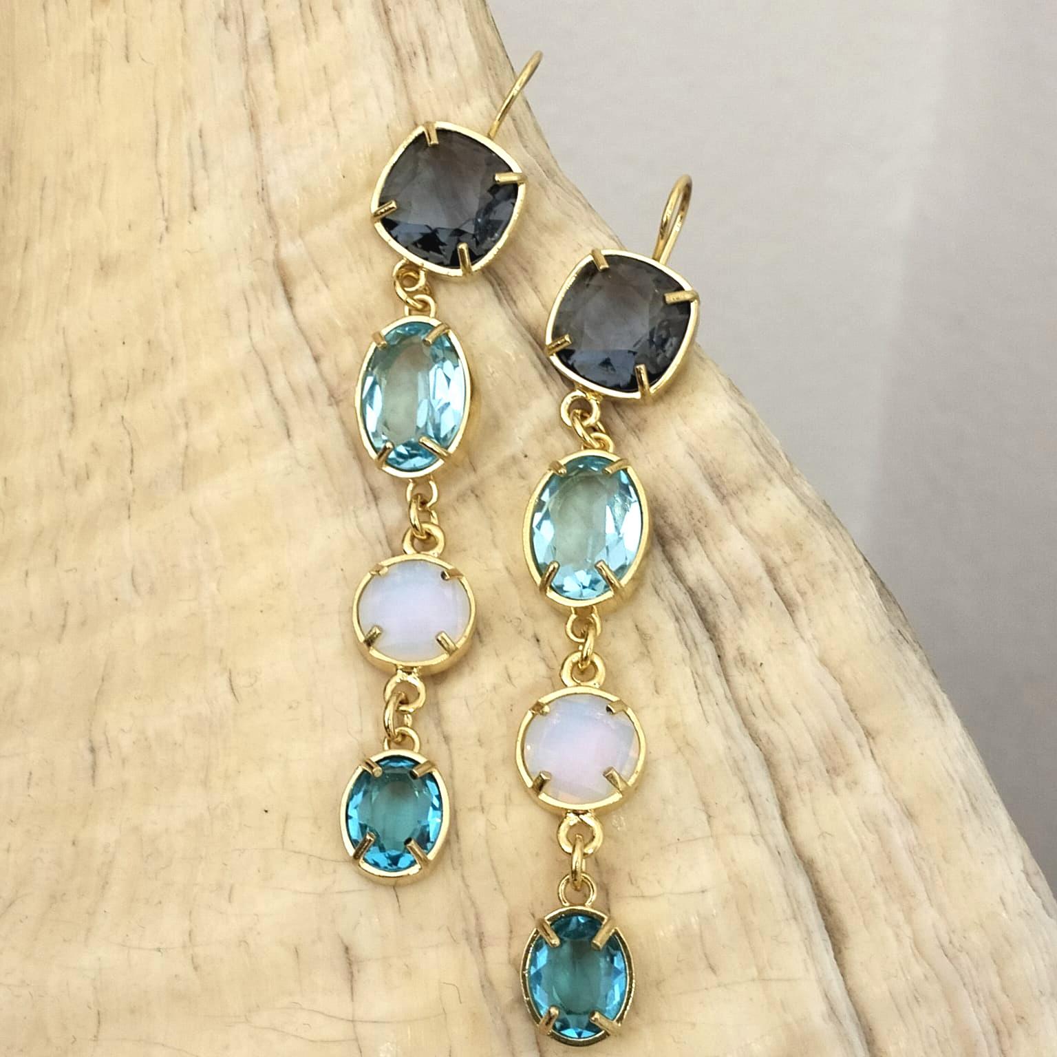 Long Patrizia Daliana earrings in 24 KT gilded bronze with briolette crystals in various shades of blue and with a touch of light given by the white opal zircon. To fix the stones to our jewels, according to the Italian goldsmith tradition, we use