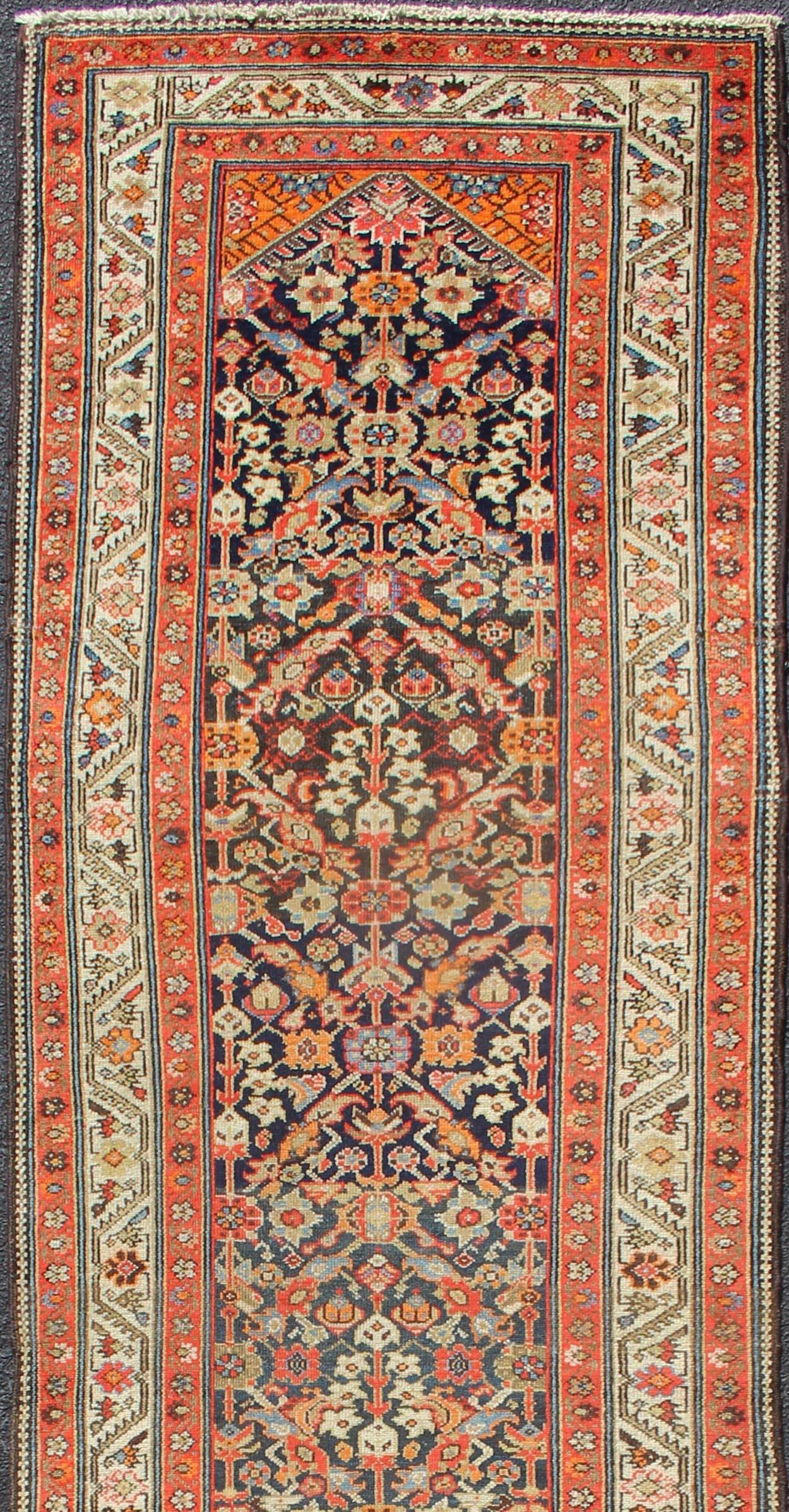 Variegated Border Malayer antique runner from Persia with geometric repeating pattern in the background which Hosts to variegated shades of blue the main border is ivory while the accent colors of orange red in the guard borders frame the main