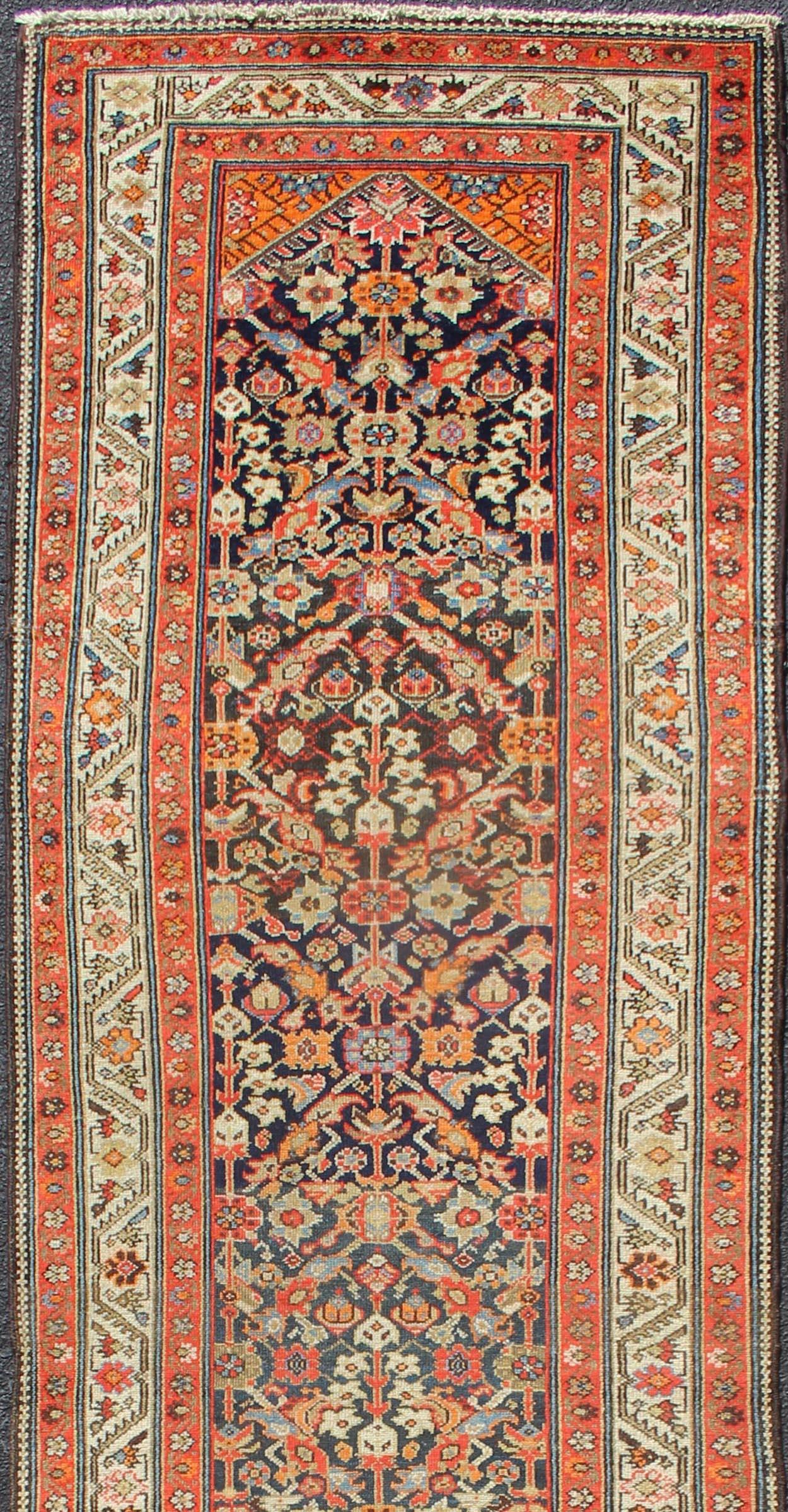 Variegated Border Malayer antiken Läufer aus Persien mit geometrischen sich wiederholenden Muster im Hintergrund, die Hosts zu bunten Schattierungen von Blau die Haupt-Bordüre ist Elfenbein, während die Akzentfarben von Orange rot in der Wache