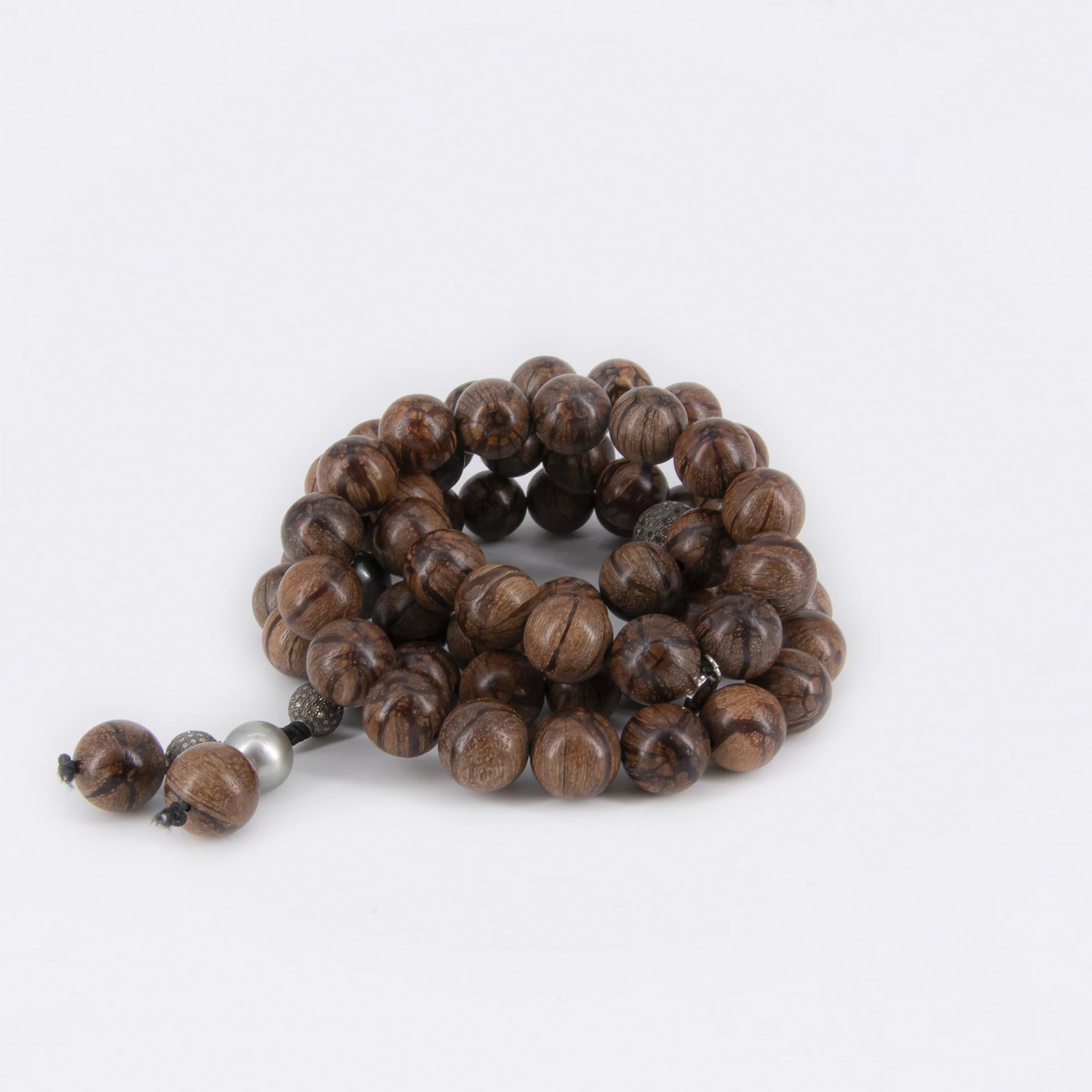 Ce magnifique collier peut être porté autour du cou et du poignet. 
Il est composé de perles en bois d'Abélia, de 2 perles pavées de diamants (12 mm), de 2 perles pavées de diamants (8 mm) en argent noirci et de 4 perles de Tahiti de différentes