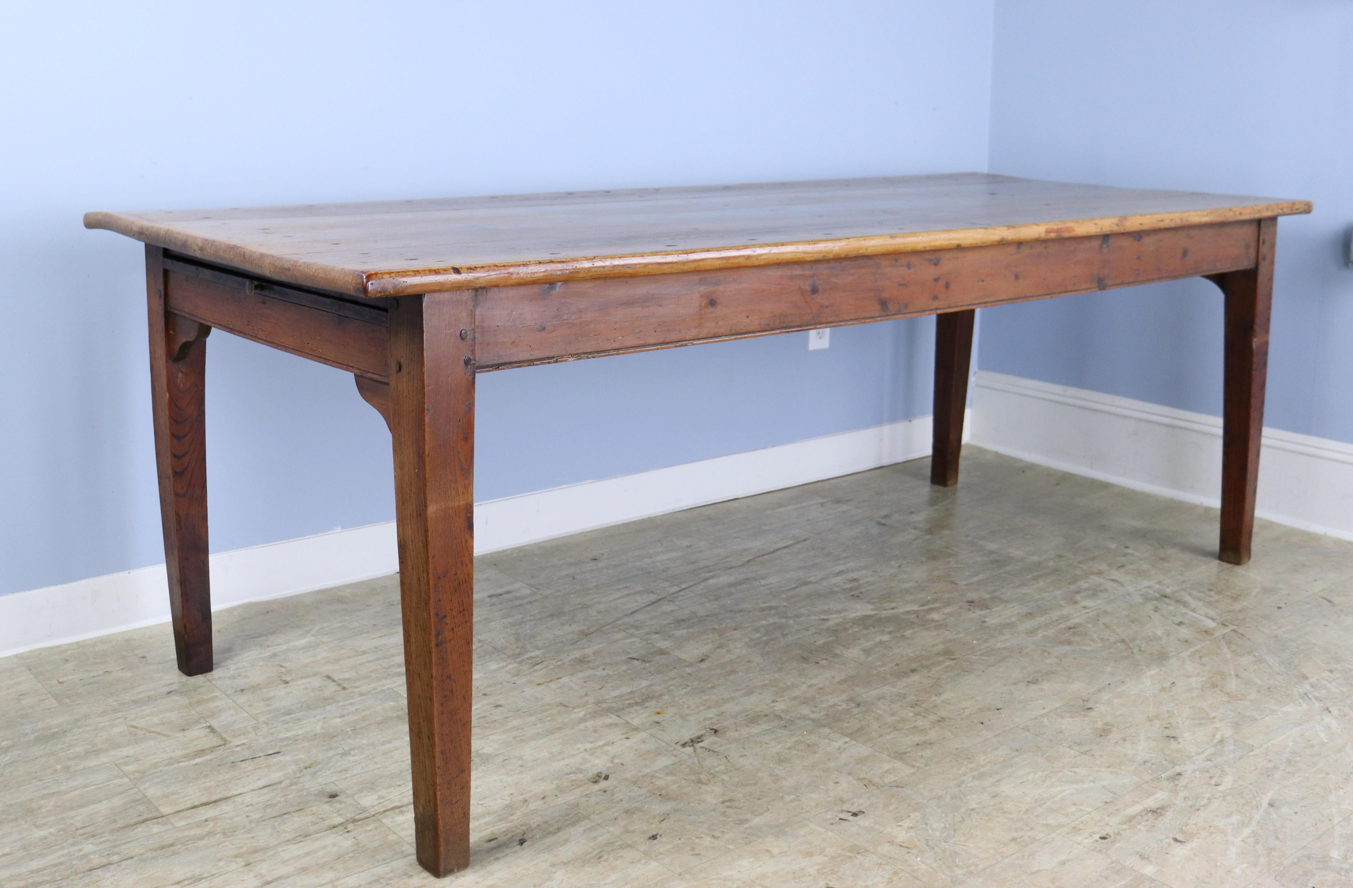 A long rustic pine farm table with glorious pine grain and interesting exposed nailheads.  The breadslide, shown, is sturdy enough for platters or additional diners.  The color and patina on this piece are really good. With 74.5 inches between the