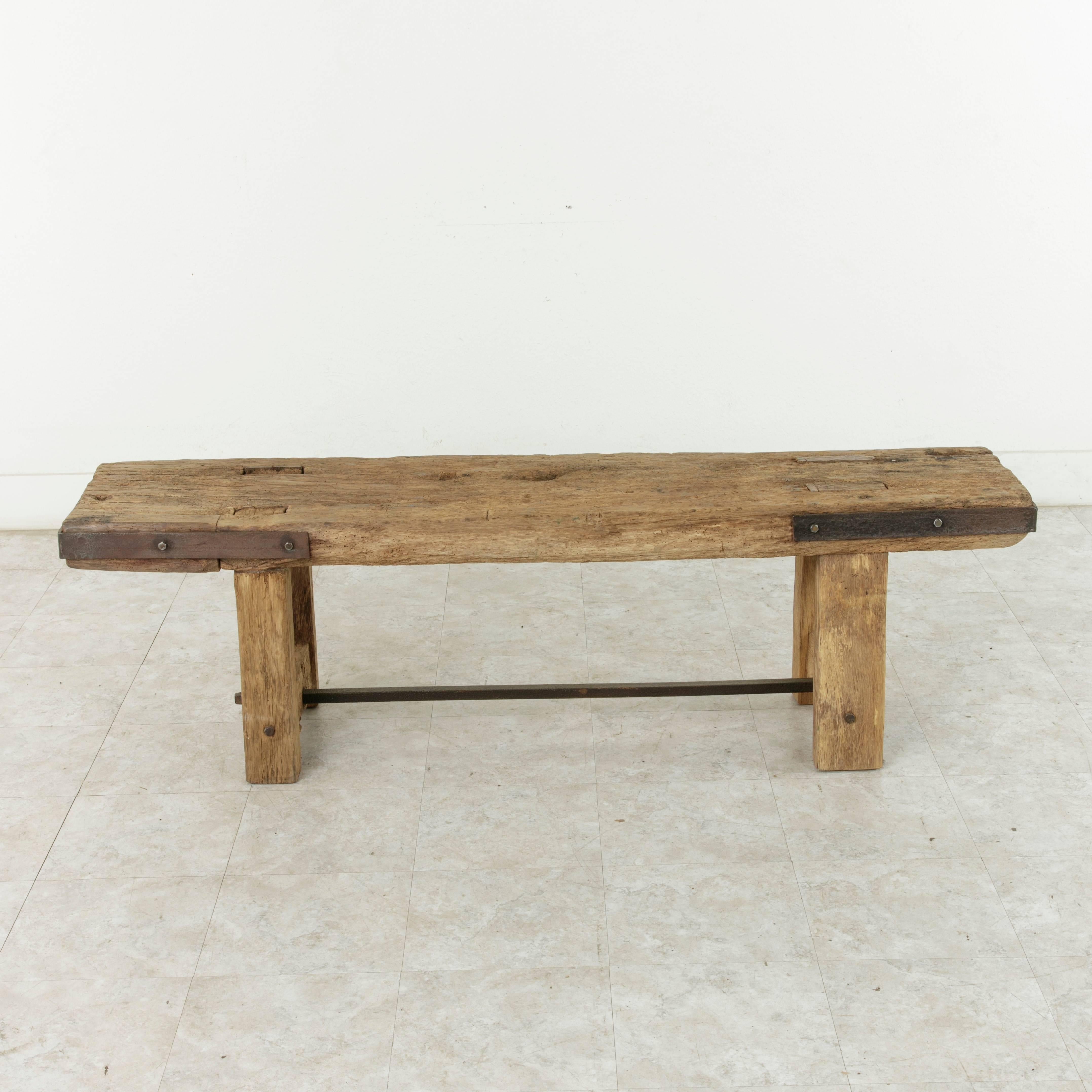 Originally used on a French farm for butchering, this long 19th century rustic oak bench features a four inch thick plank for the seat and is capped on both ends with an iron strap. The sturdy legs are constructed using mortise and tenon joinery and