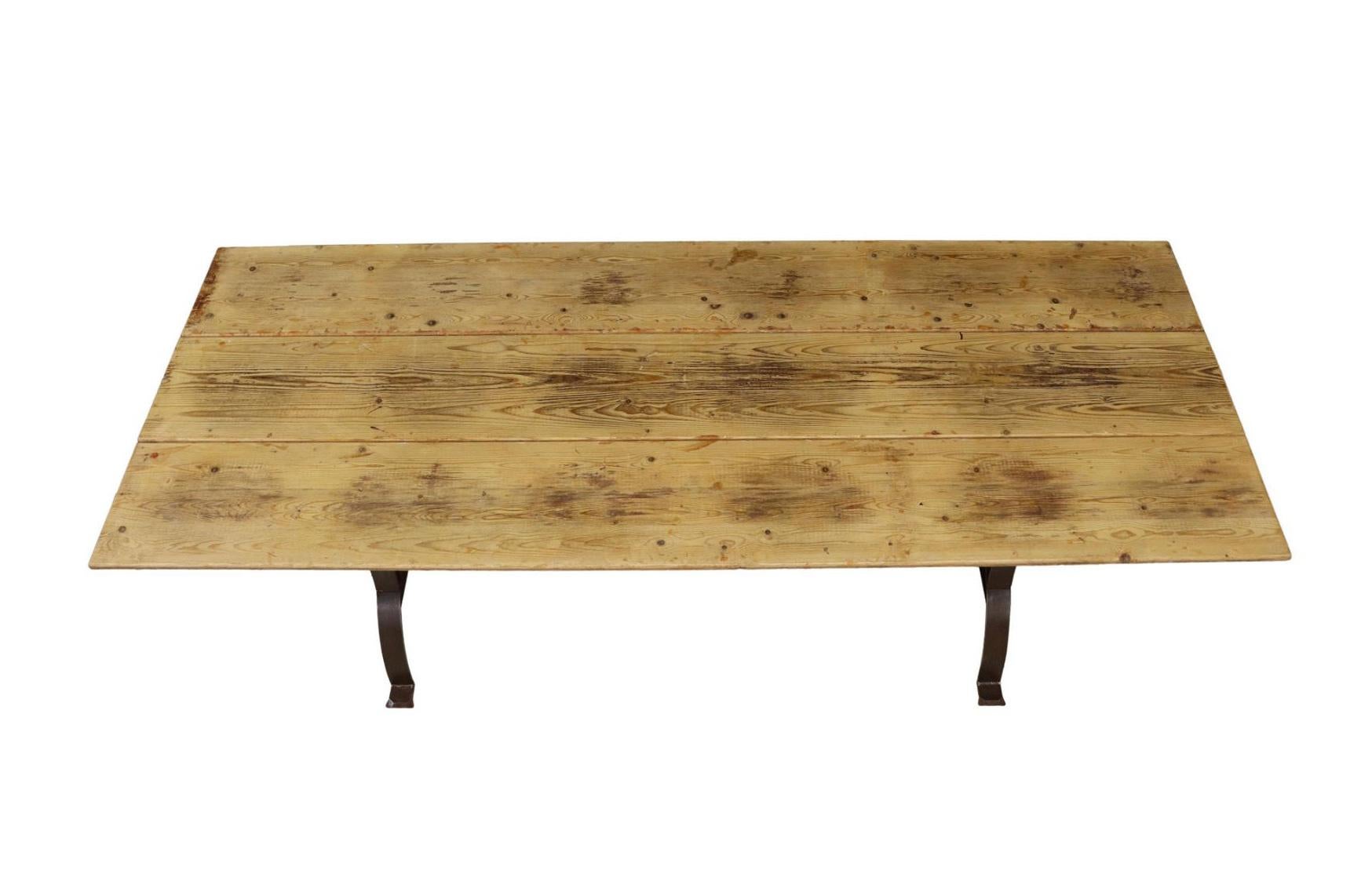 Grande table de salle à manger rustique, fin C.I.C.. Cette table présente un plateau en pin ciré, des supports en curule en fonte, reliés par un croisillon.

Dimensions
 environ 30 
