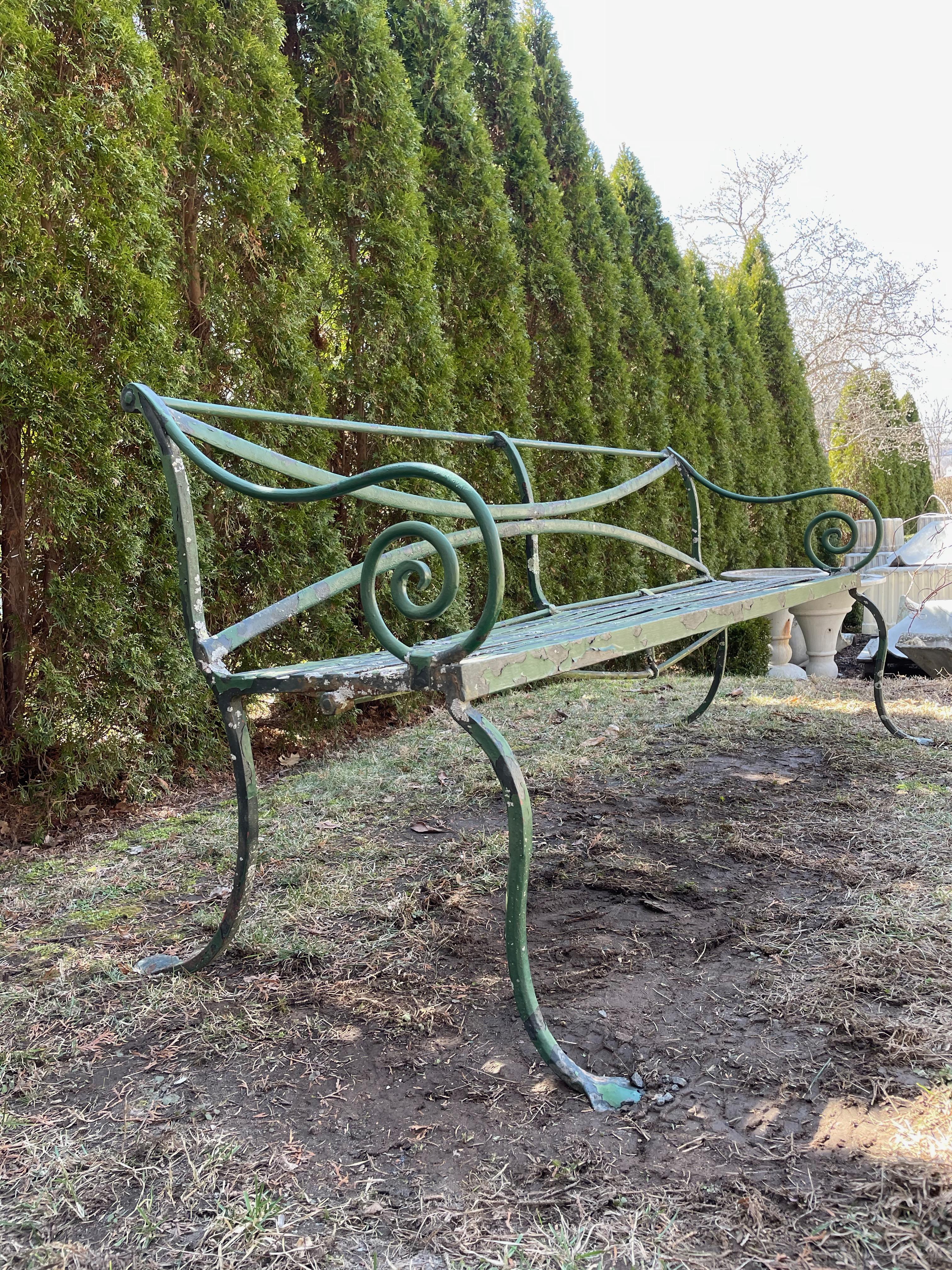 This is a fabulous hand-wrought iron bench in all respects and very comfortable as well. With an X-form back, slatted seats, scrolled arms, cabriole legs and two-penny feet, it ticks all our boxes. The surface comprises worn green paint that, in