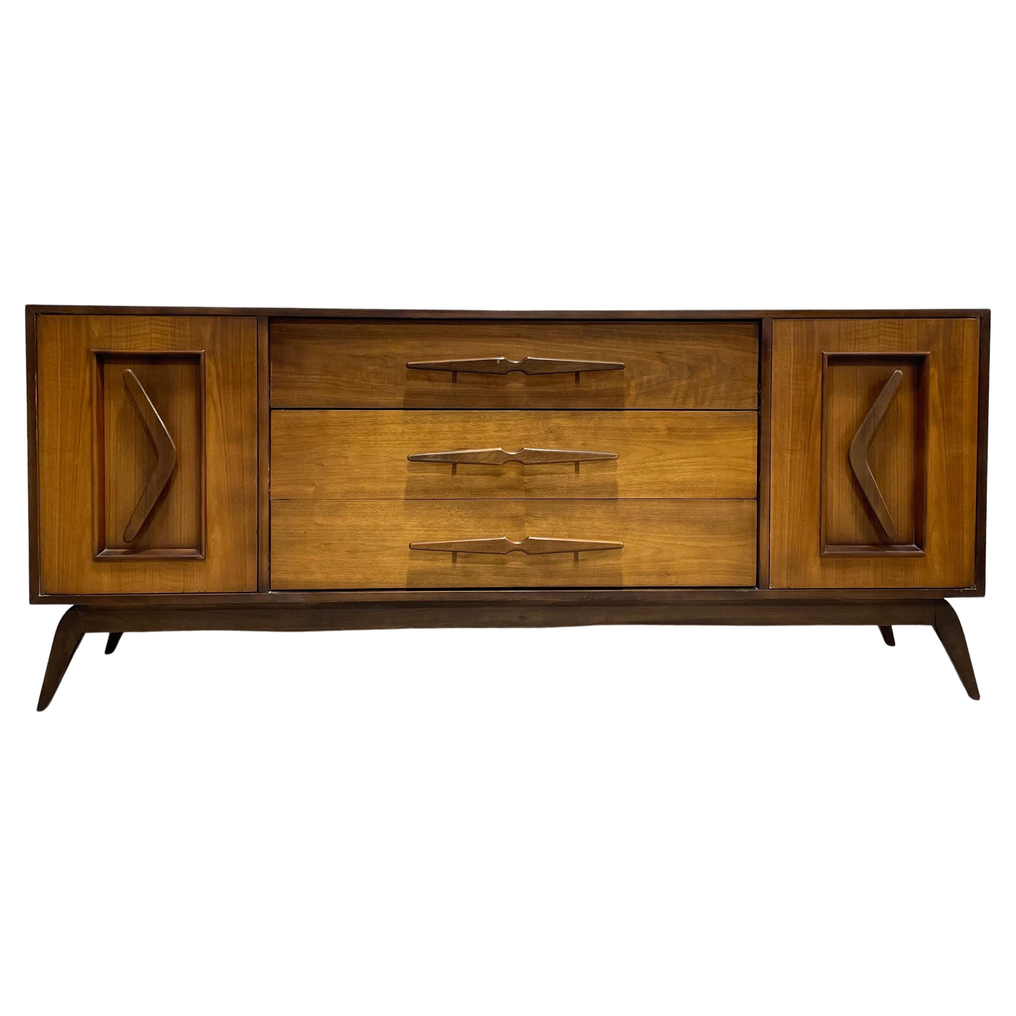 Mid Century Modern Long Dresser / Sideboard with boomerang hand-pulls along the side cabinet doors, sculpted center pulls and splayed legs along the solid base. The dresser offers loads of storage space - a total of SIX deep and spacious drawers -