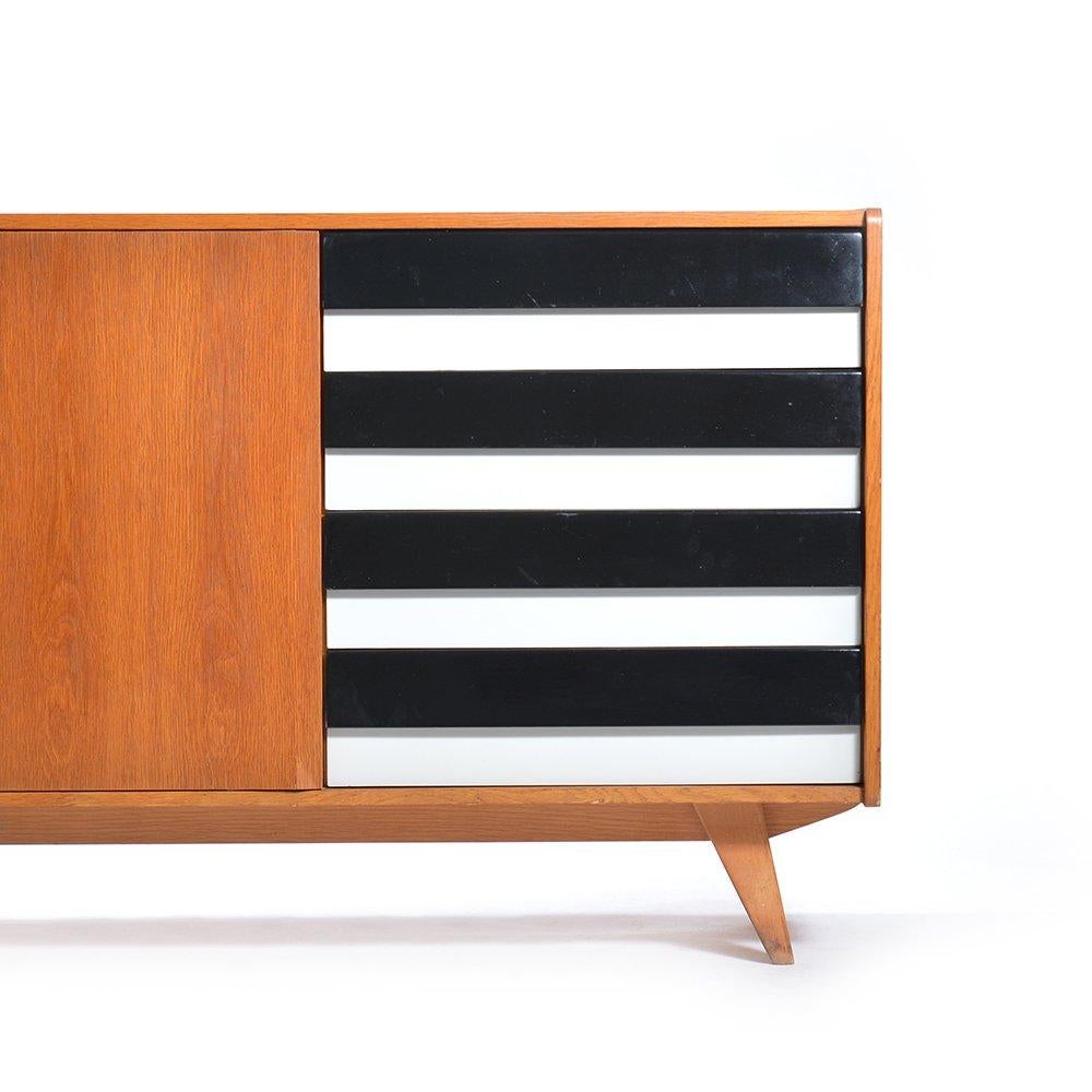 This midcentury sideboard by Jiri Jiroutek is completely restored and in beautiful condition. The sideboard represents the best of Czechoslovakian design of the 1960s. The left side has opening doors and compartment. The right side has four drawers