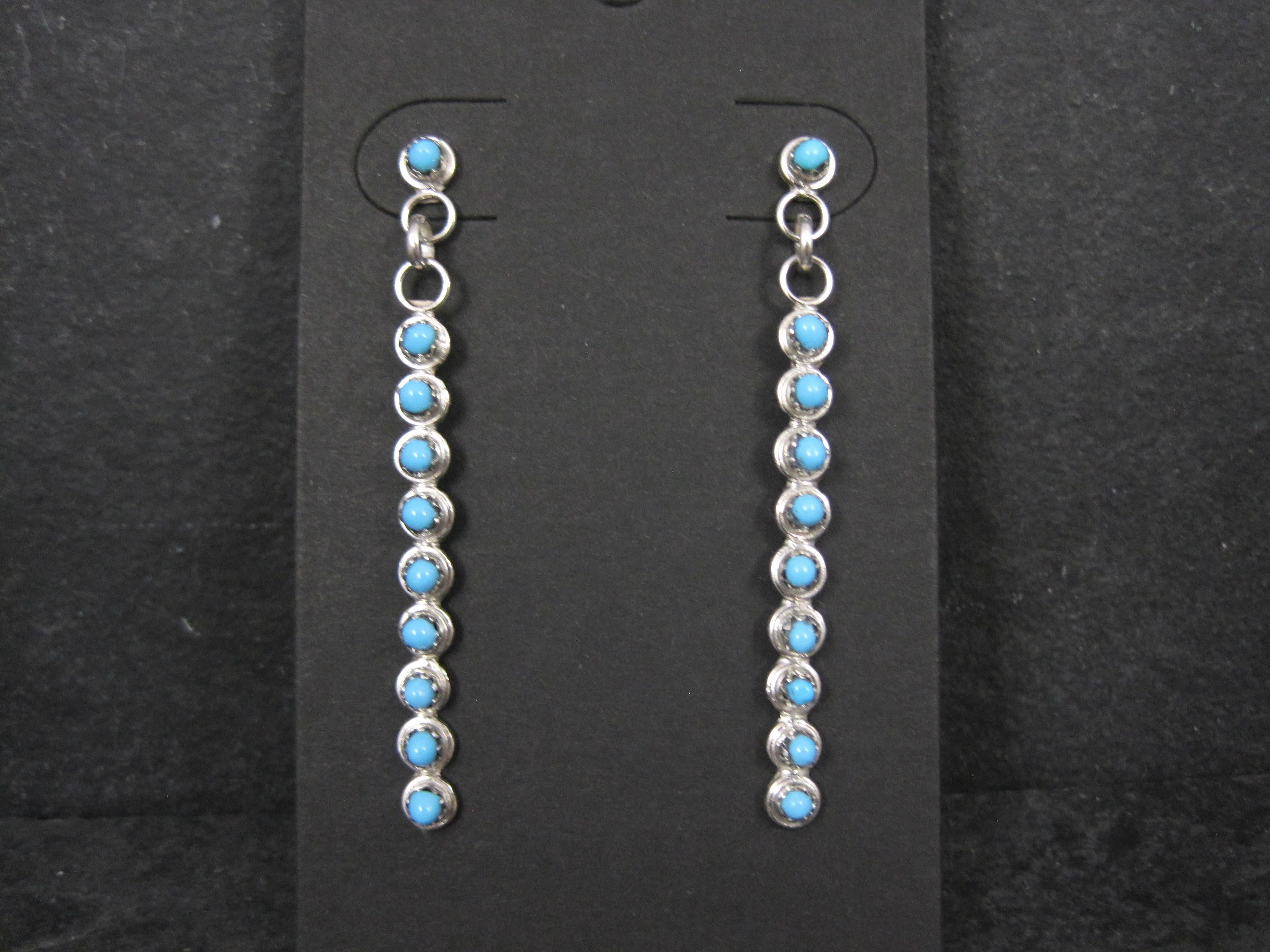 These gorgeous Southwestern earrings are sterling silver with snake eye cut turquoise gemstones.
Made by Zuni silversmith Henrietta Quetawki.

Measurements: 3/16 by 2 inches
Weight: 3.5 grams

Condition: New