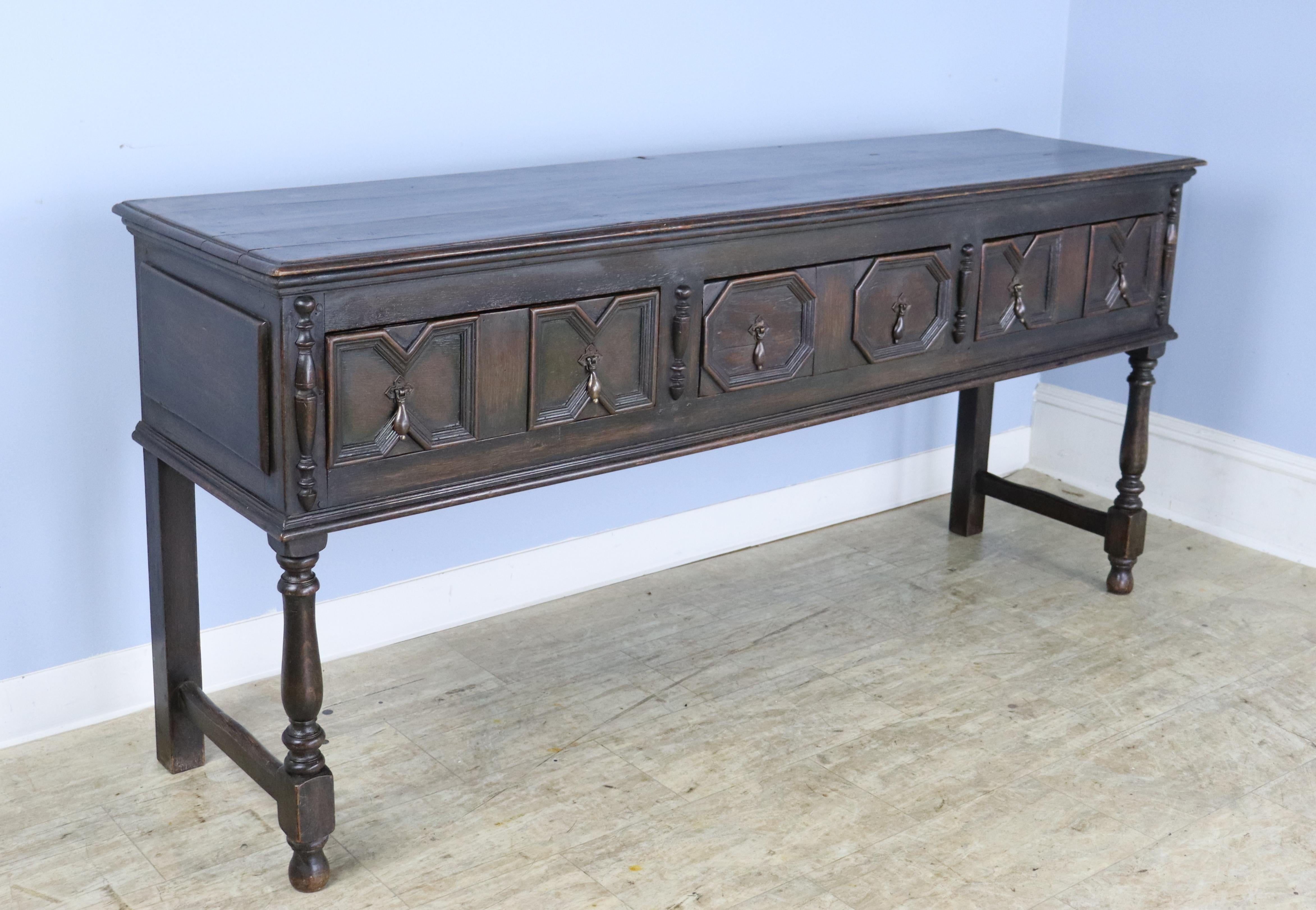 A handsome English dark oak server, console or sideboard with a geomtric pattern on the 3 drawer fronts.  Although this piece is mid 19th Century, it has all the sensibilities of a much earlier period, specifically Jacobean.  Original brass teardrop