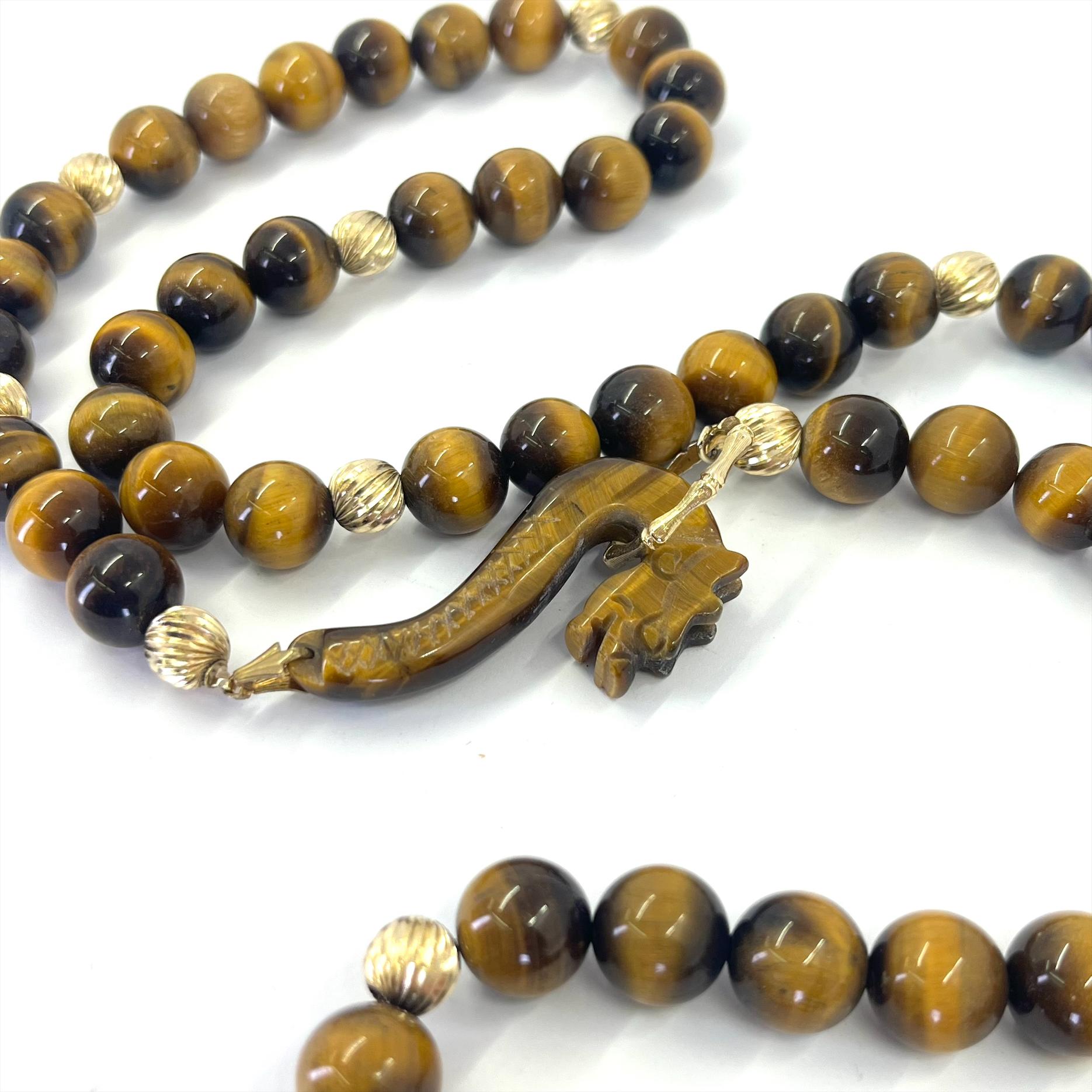 14 Karat Yellow Gold Vintage Necklace Featuring 10mm Tiger Eye Beads and 6mm Ridged Gold Beads with Carved Dragon Toggle Clasp. Adjustable Length Up to 34 Inches.