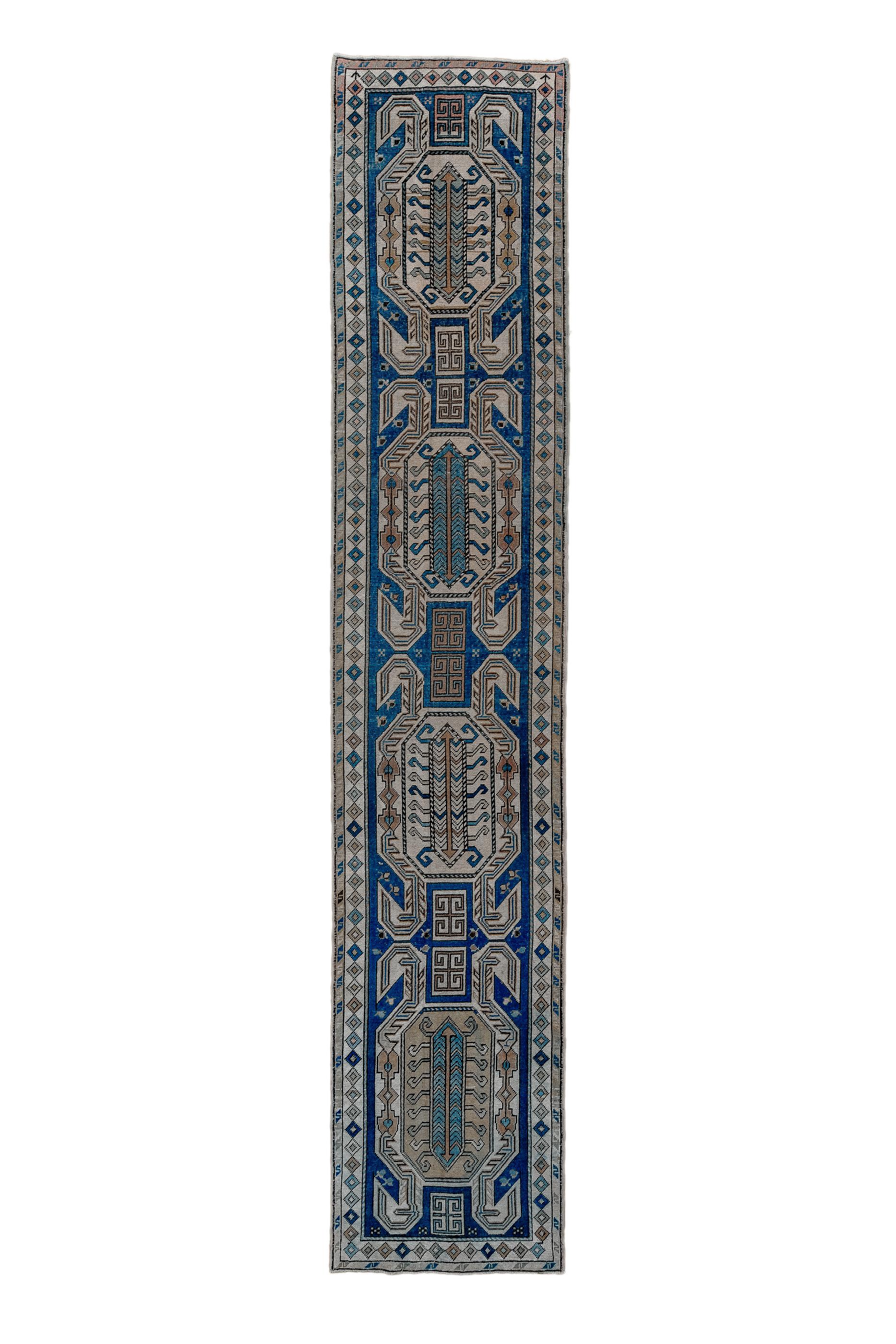 This usefully narrow kenare (runner) shows a pattern of four four hooked cartouches, all with centipede centres, on a royal blue ground. Panels of two double E’s connect the cartouches into a pole. Ecru main border of chains of small, nested
