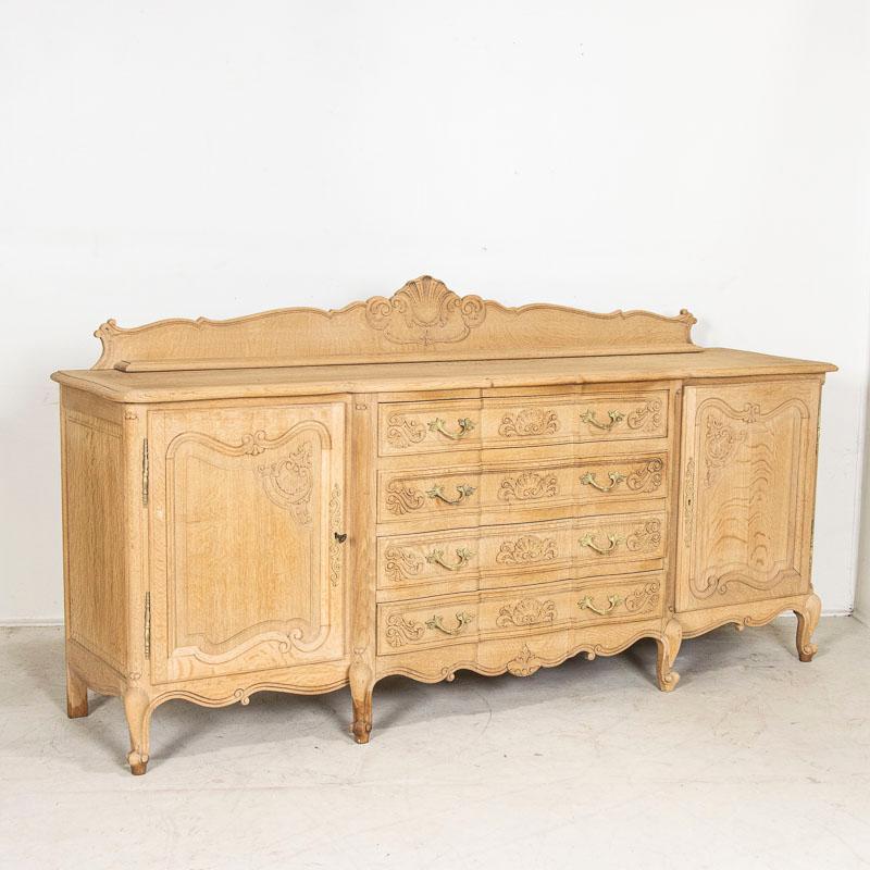 This long sideboard shows off its French style in the panels and lovely details along the skirt and drawers. Carved details include flourishes along the drawers, door panels and cabriolet feet. The bleached finish gives it a fresh and welcoming look