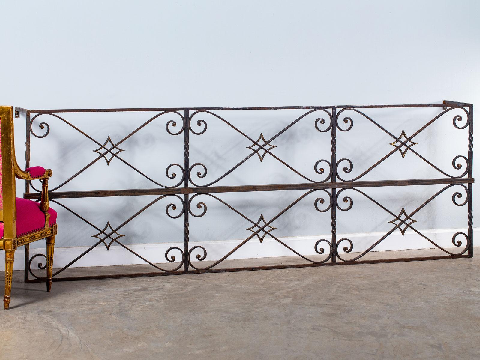 A very long vintage French architectural salvage reclaimed iron console table circa 1940 set with six panels of decorative motifs. The use of hand forged iron in a torsade pattern in conjunction with diagonal scrolled elements is set of with central