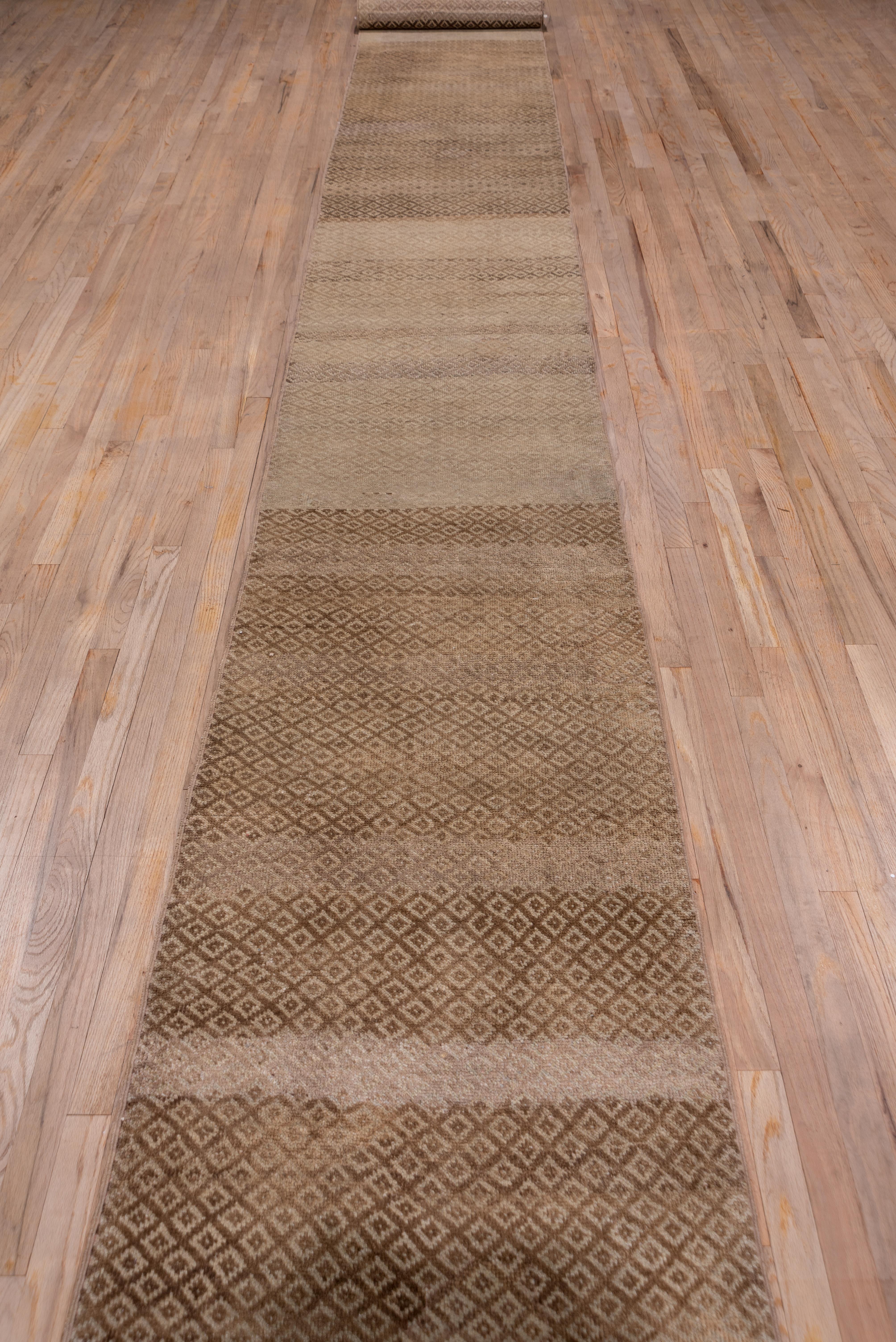 This good pile, borderless rustic Turkish runner displays an abrashed small lozenge pattern on a rust red to light buff field.