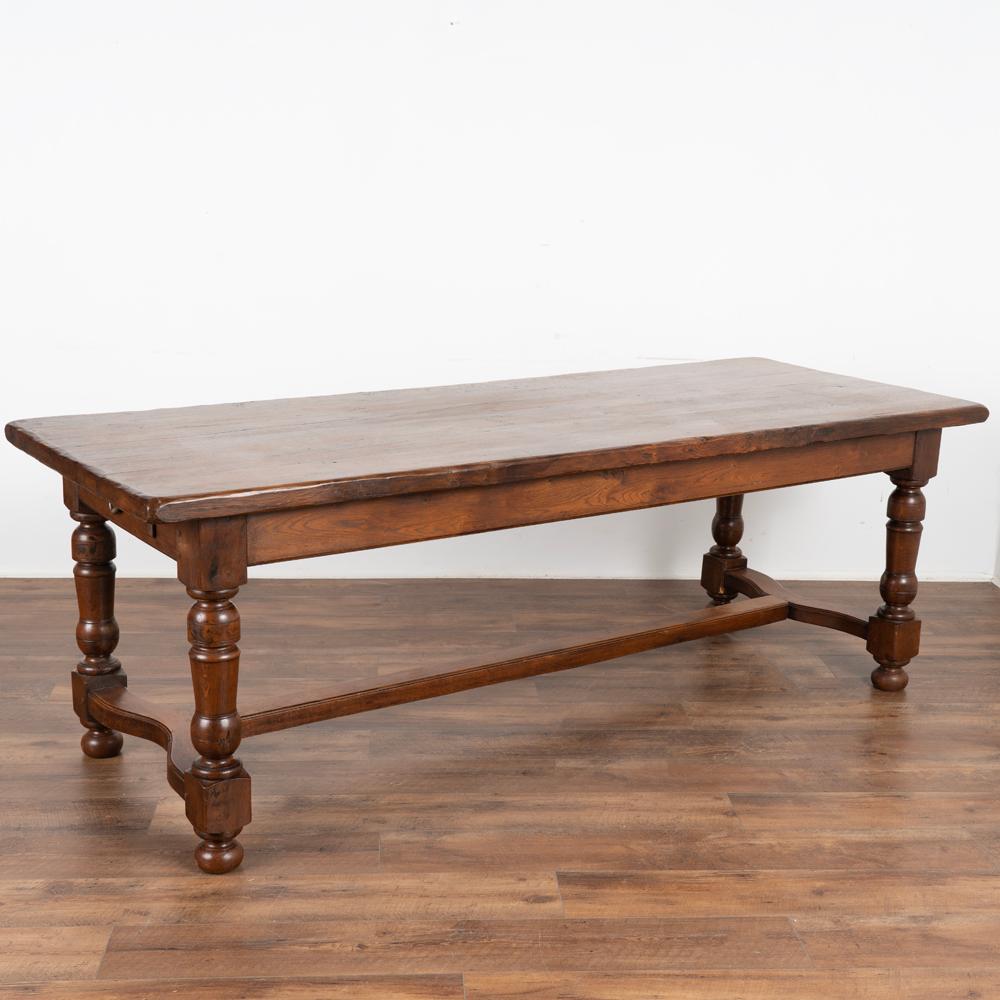 The deep aged patina of the beautiful walnut wood draws one to this handsome refectory or library table from France.
The turned legs and slight curve to the end of the trestle base add to the visual appeal.
There is a single drawer at one narrow