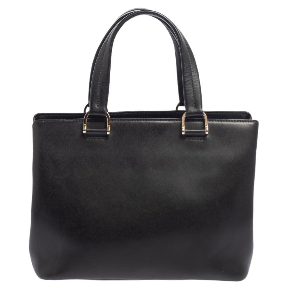 This Longchamp tote is stunning and functional. Crafted in black leather, it comes with dual-top rolled handles to lend convenience and the brand logo on the front. The nylon-lined interior is secured with a hook closure and houses a zipped