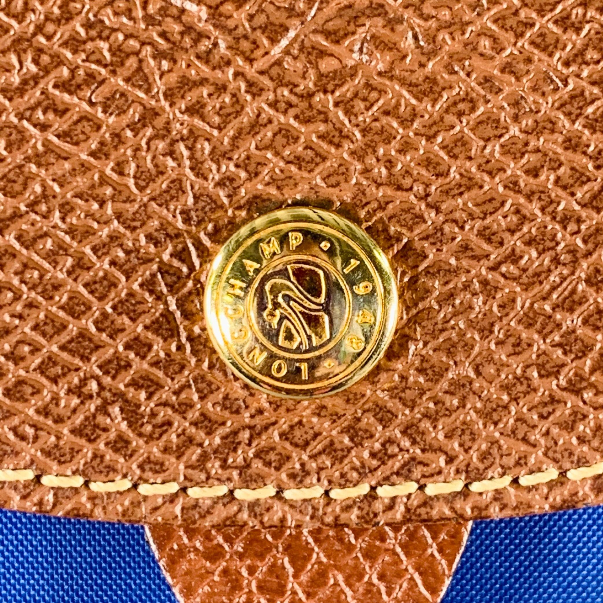 LONGCHAMP backpack
in a jewel tone blue nylon featuring brown leather trim details, one compartment with pocket, and zip top closure. Very Good Pre-Owned Condition. Minor signs of wear. 

Measurements: 
  Length: 10 inches Width: 3.75 inches Height: