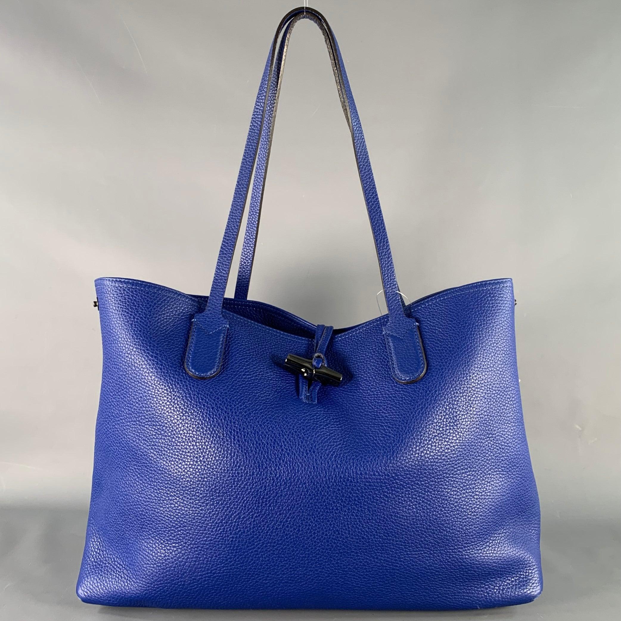 LONGCHAMP tote
in a blue pebble grain leather featuring top handles, spacious interior compartment with key clasp, side snaps to change the shape of the bag, and metal toggle closure.Good Pre-Owned Condition. Moderate marks inside, as is.