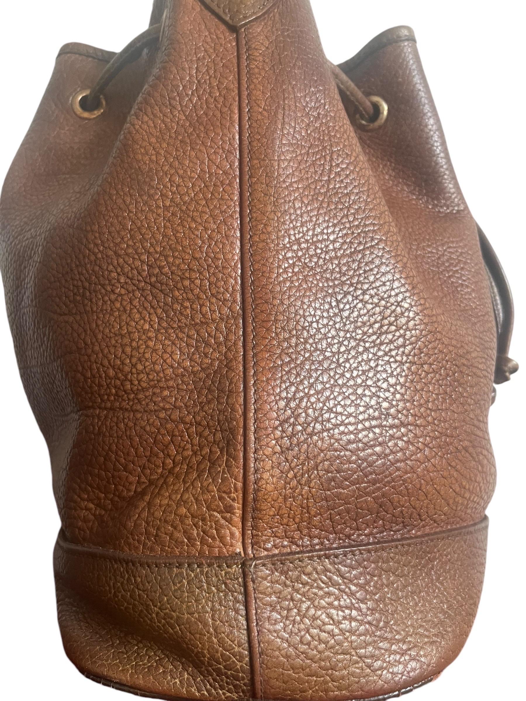 Very pretty Longchamp shoulder bucket bag in brown grained leather. The bag has a leather drawstring to open and close it.
The Longchamp leather logo is present on the front of the bag. The gold metal parts are stamped Longchamp Paris.
This bag is a