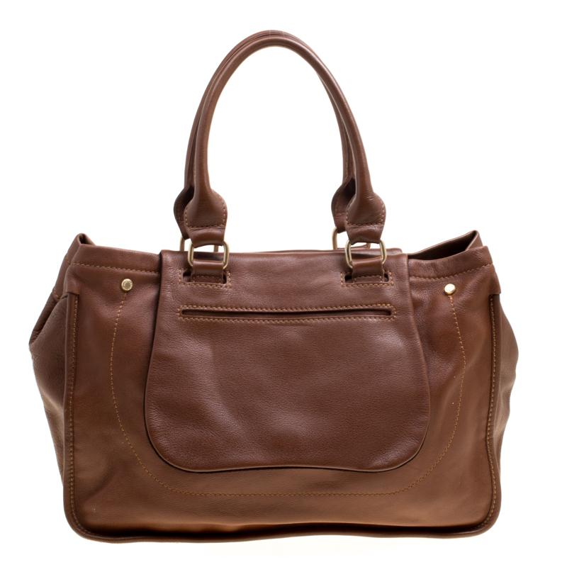 This opulent Balzane Roots top handle bag by Longchamp has the flair to complete any look. Crafted from brown leather, it features dual top rolled handles and an interesting flap design at the front. This bag is accentuated with gold-tone hardware