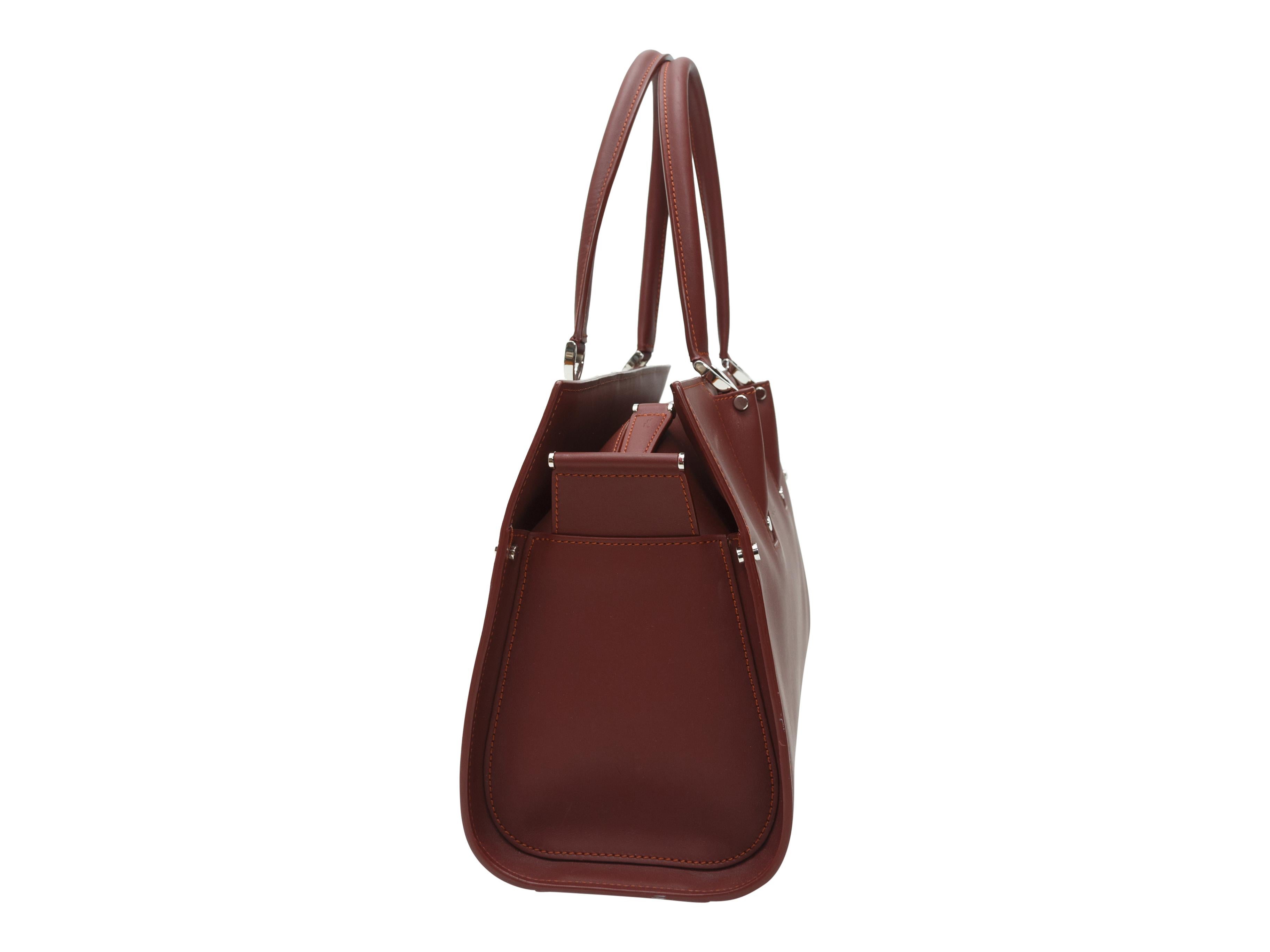 Product details: Burgundy rectangular leather handbag by Longchamp. Dual rolled top handles. Silver-tone hardware. Zip closure at top. 14