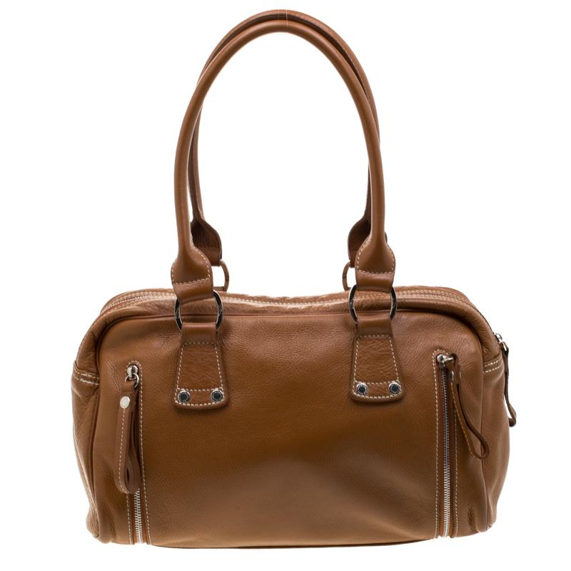 This bag from Longchamp is spacious and the perfect travel accessory. The durable bag is crafted from brown leather. It features dual top handles, a front zip pocket, and chain trims that run through the bottom. The zip-top closure opens to a roomy