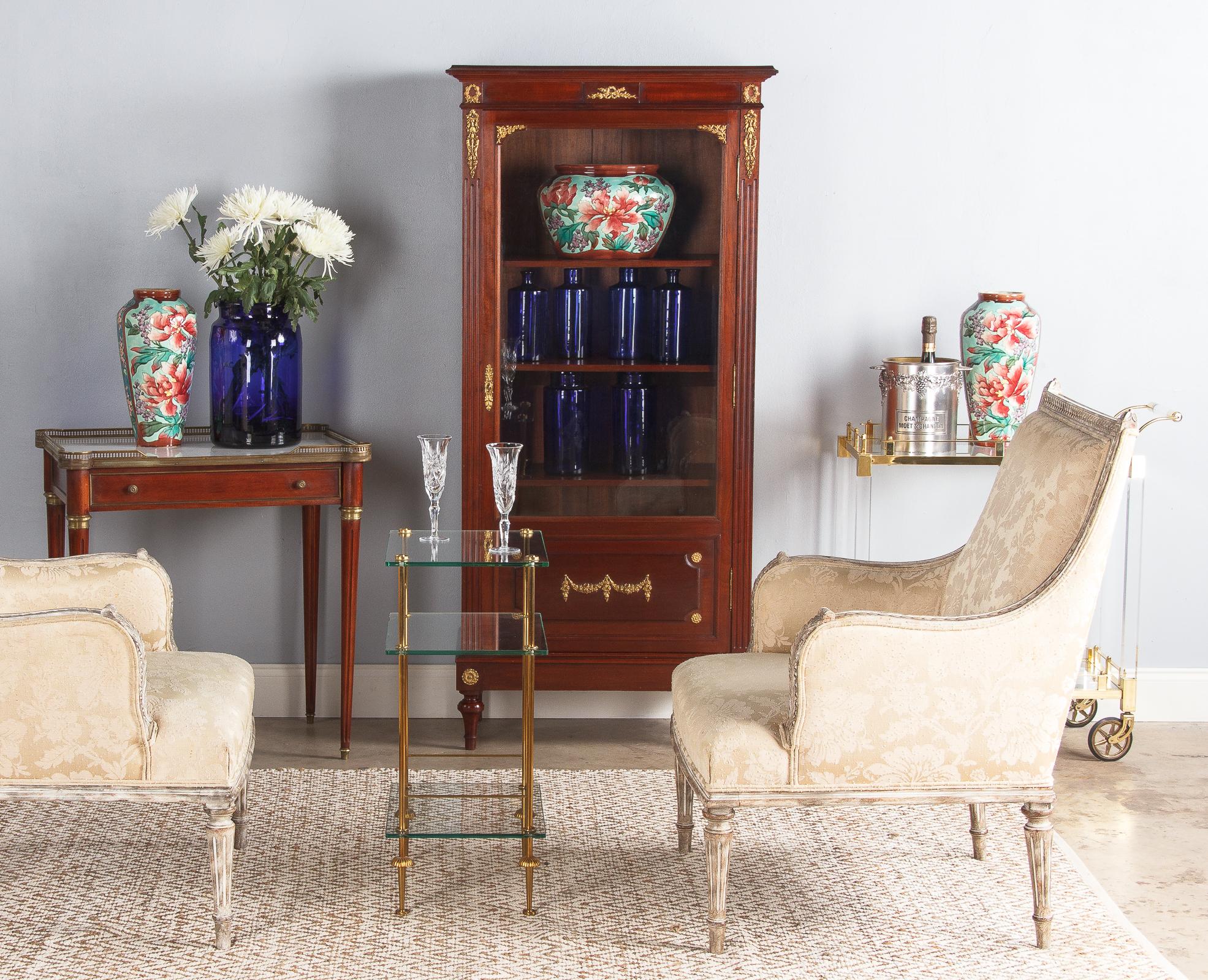 A vibrant three-piece ceramic garniture set with colorful flowers from Longchamp Barbotine, circa 1900. Two tall vases with simple rims, high and sloping shoulders, and body that tapers towards the base. The single low vase has the same general