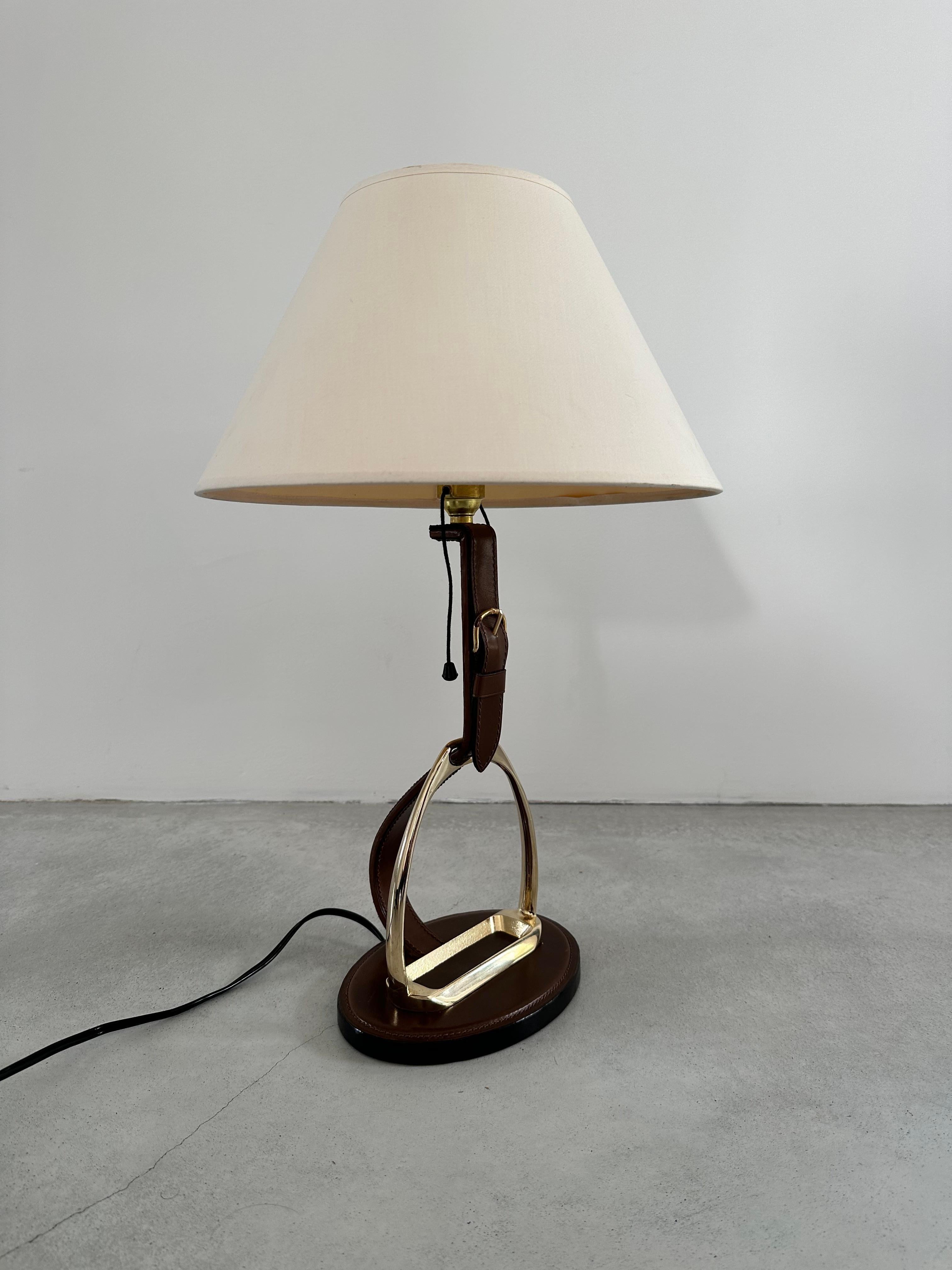 A thoroughbred French 1960's lamp, design by Longchamp Paris 
for your writing table. 

A solid brass stirrup mounted and wrapped in saddle-stitched leather with brass buckle. Very 

The Longchamp table lamp brings elegance and sophistication to
