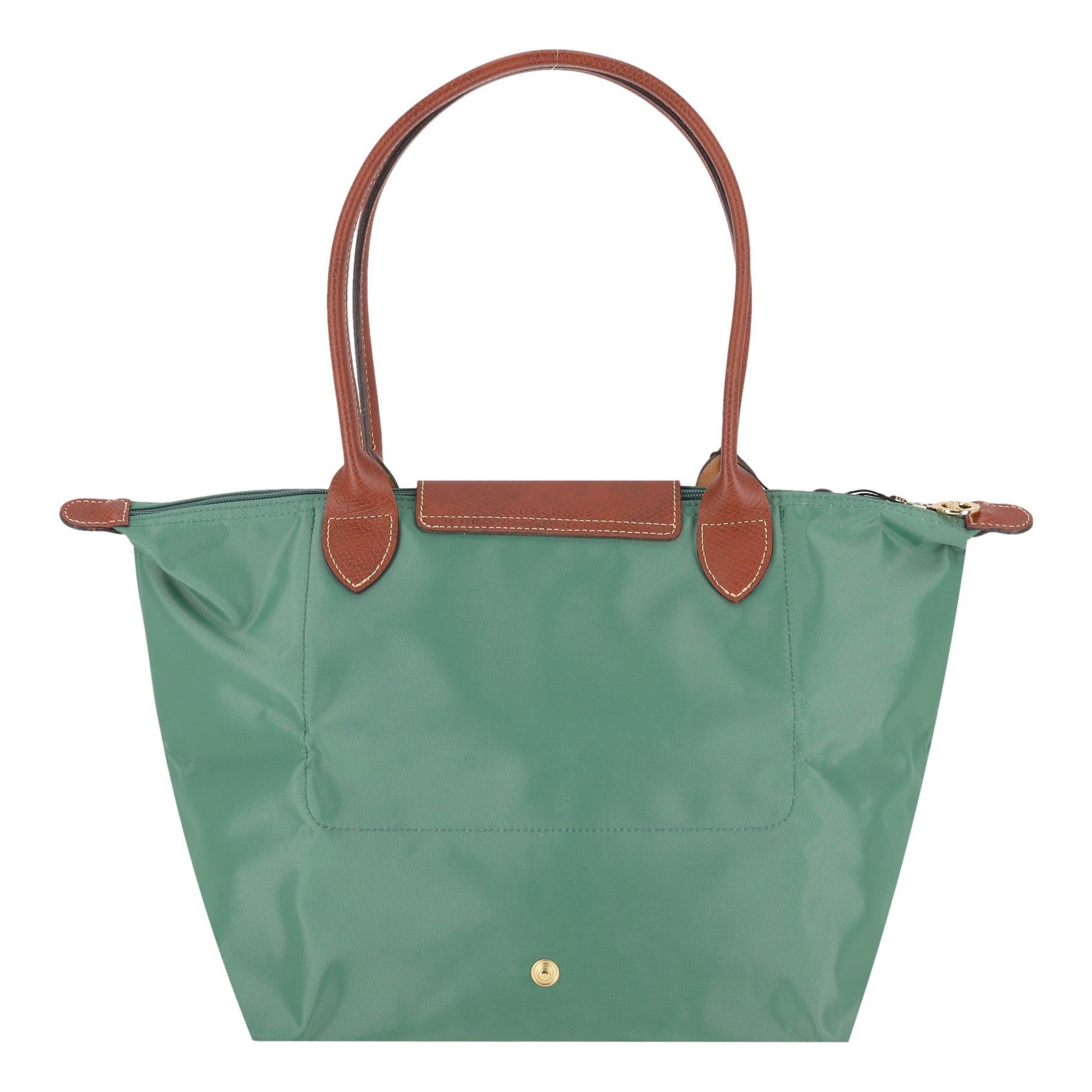 Longchamp Le Pliage Original Large Tote Bag

Green nylon tote bag with brown leather details.

Featuring dual tope handles and snap and zip top closure leading to spacious interior.

Detailed with logo embossment to the leather and gold logo charm