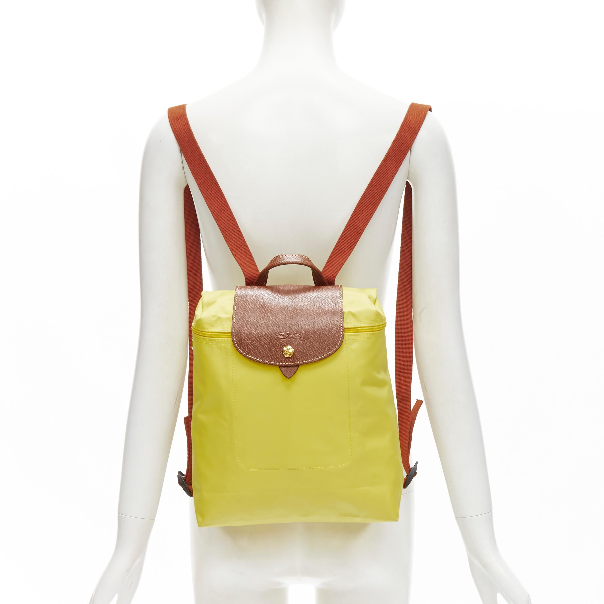 LONGCHAMP Le Pliage yellow nylon brown canvas trim foldaway backpack bag 
Reference: CLCN/A00006 
Brand: Longchamp 
Collection: Le Pliage 
Material: Nylon 
Color: Yellow 
Pattern: Solid 
Closure: Zip 
Extra Detail: Top zip closure with button top