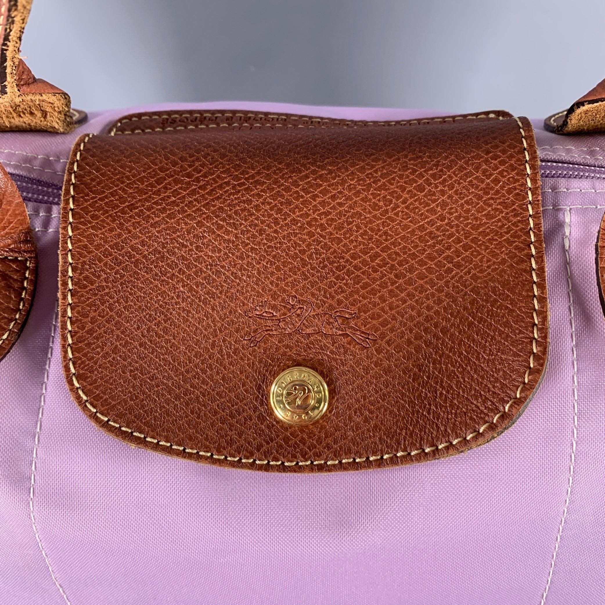 LONGCHAMP handbag
in a lilac purple nylon featuring a tote style, brown leather trim details, and zip closure. Very Good Pre-Owned Condition. Moderate marks and signs of wear, worn corners. As is. 

Measurements: 
  Length: 11.25 inches Width: 8