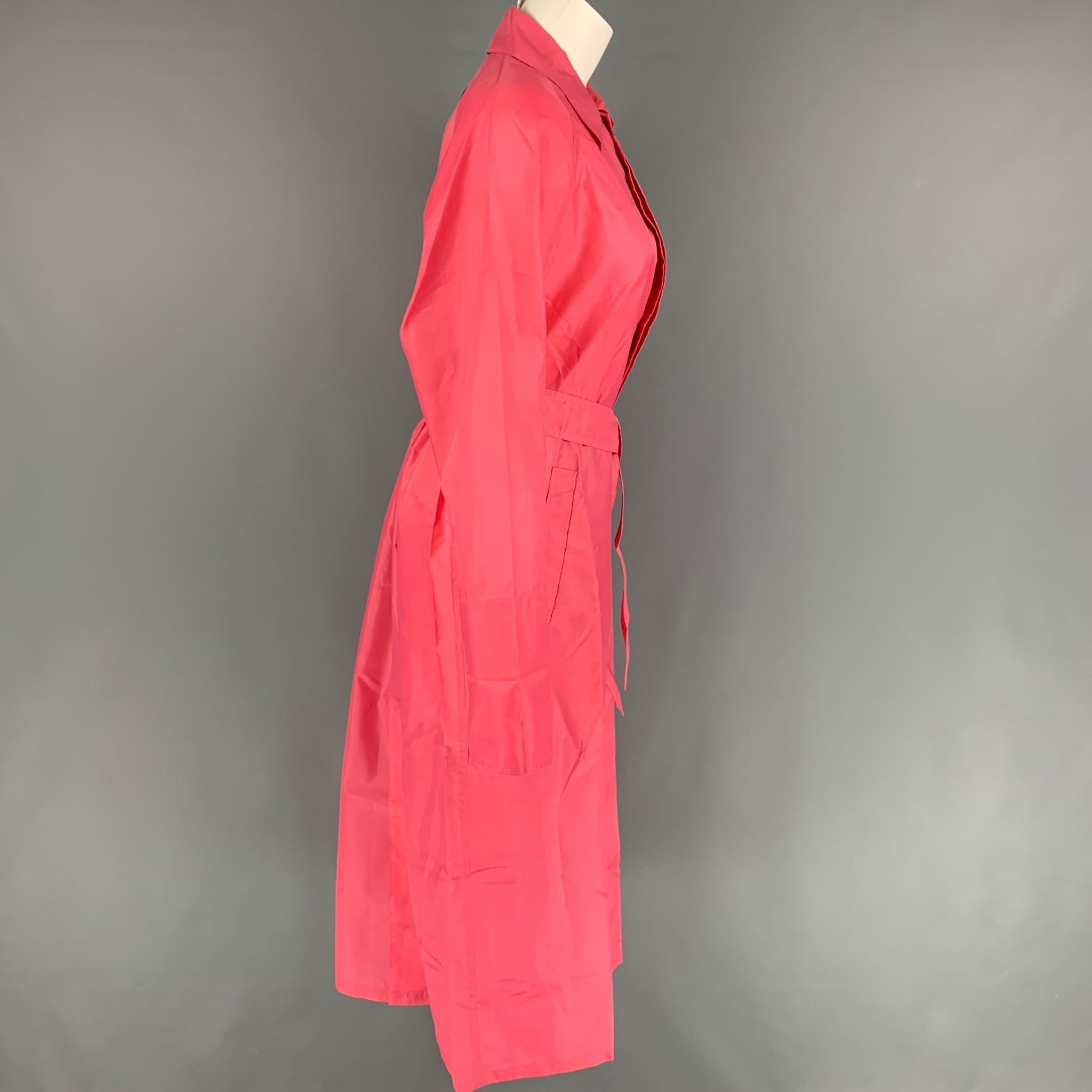 LONGCHAMP raincoat comes in a pink nylon featuring a spread collar, slit pockets, belted, and a hidden placket closure. Comes with pouch.

Very Good Pre-Owned Condition.
Marked: S

Measurements:

Shoulder: 17 in.
Bust: 46 in.
Sleeve: 24 in.
Length: