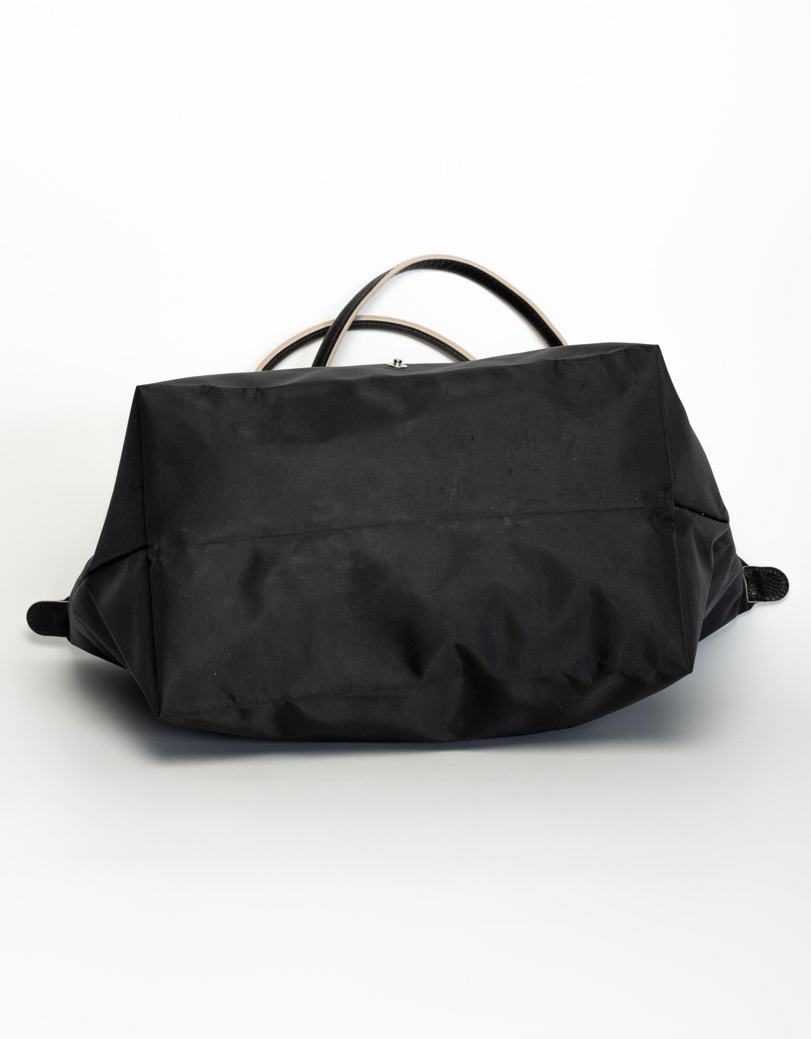Longchamp classic Le Pliage bag (‘folding’ in French) in black nylon fabric with leather straps. Featuring top zipper closure and an open interior. Perfect for traveling.

COLOR: Black
MATERIAL: Nylon
MEASURES: H 12” x L 19.5” x D 7.5”

Made in