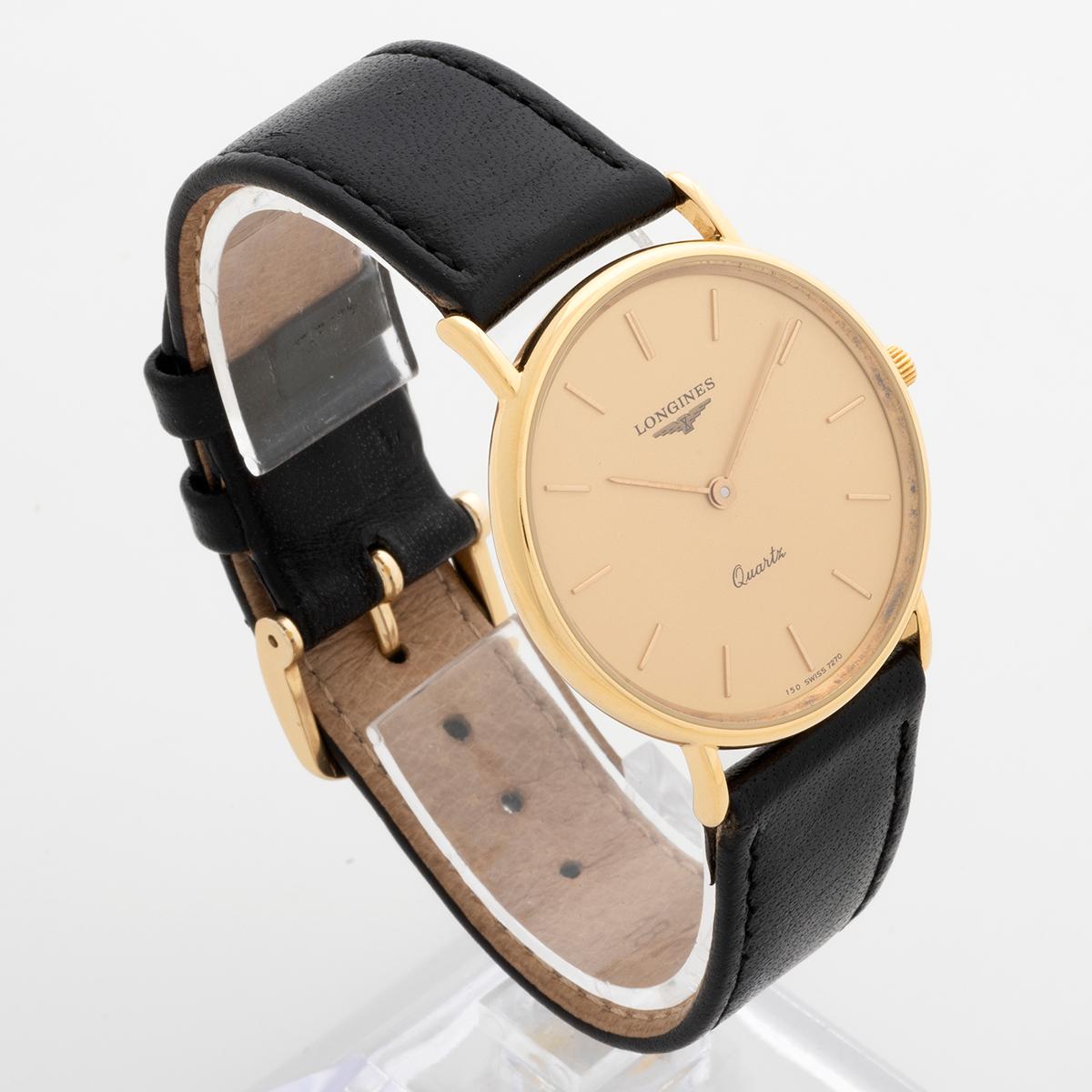 Unsere Longines La Grande classique Referenz L4.627.8 ist eine attraktive, schlanke Armbanduhr mit Quarzwerk, einem Gehäuse aus 18 Karat Gelbgold von 32,5 mm (34 mm mit Krone), einem champagnerfarbenen Zifferblatt und einem schwarzen Lederarmband